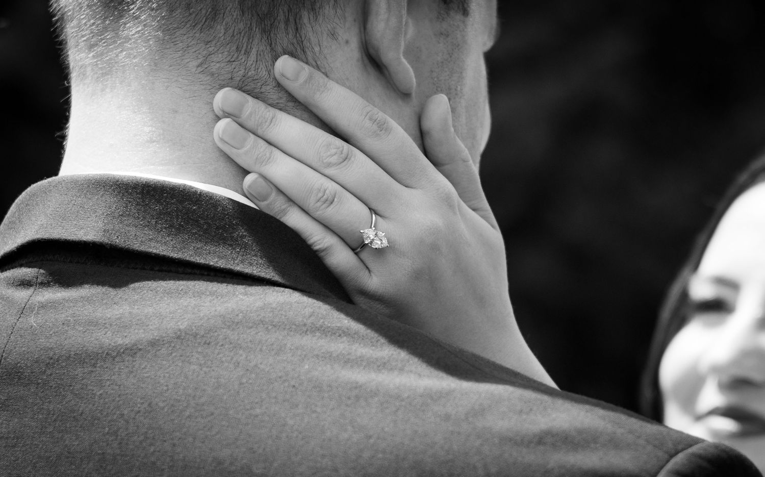 A series of black and white wedding photos showing romantic moments and ring details between a couple.