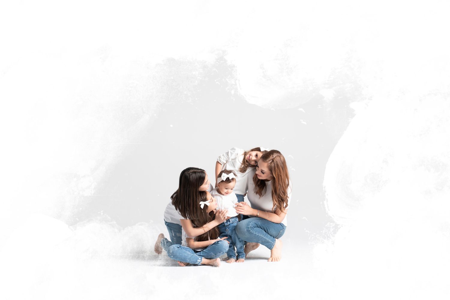 People in casual attire sit on the floor together laughing and having fun against a white background.
