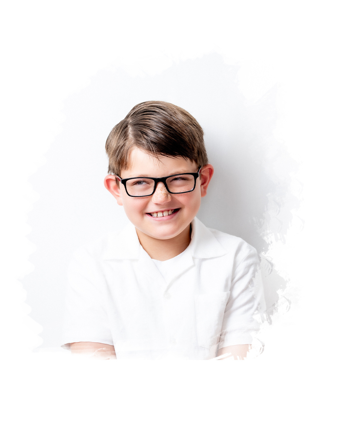 Young student in black rimmed glasses and white shirt smiles brightly against white background.