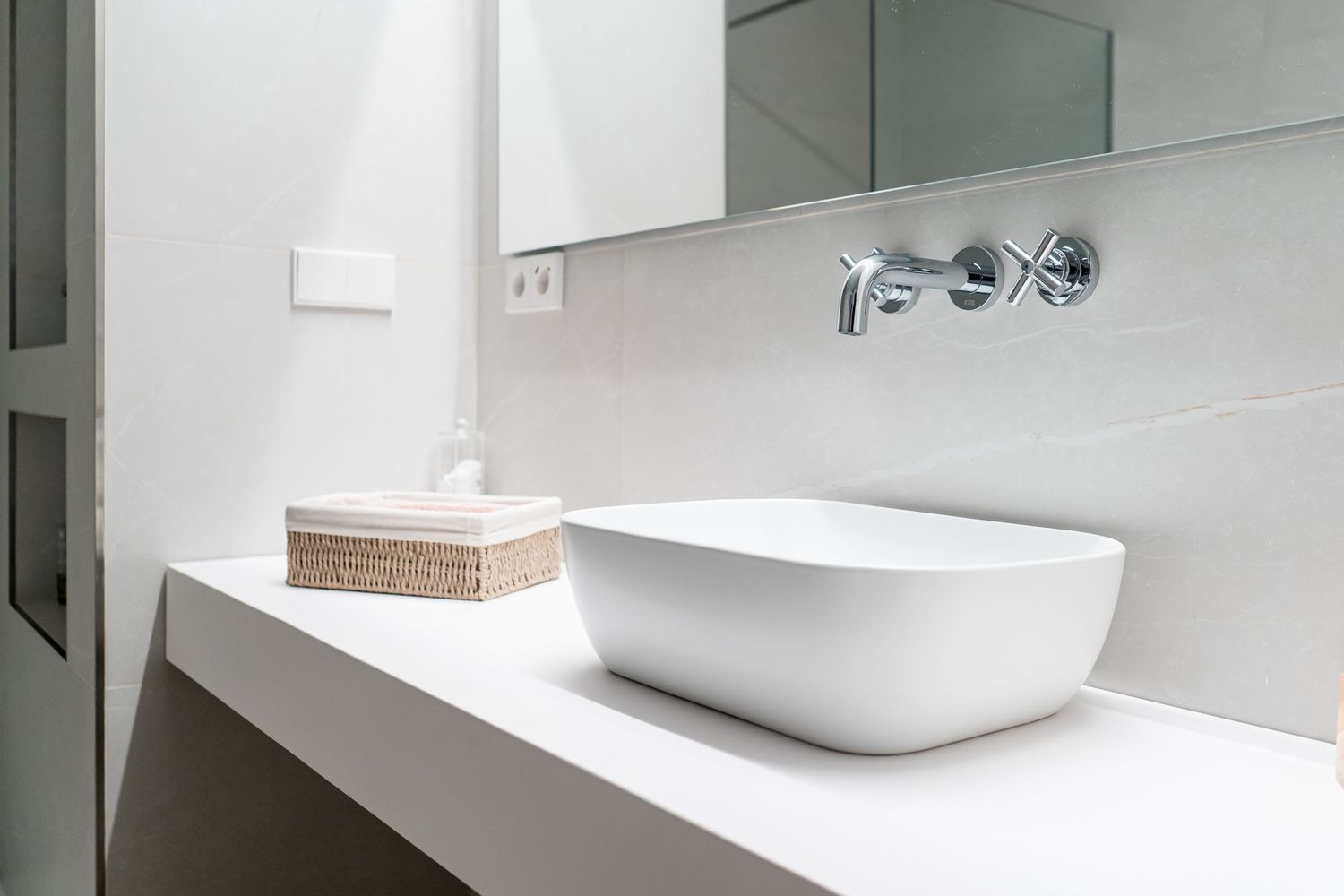 Contemporary white bathroom with sleek vessel sink and wall-mounted faucet.