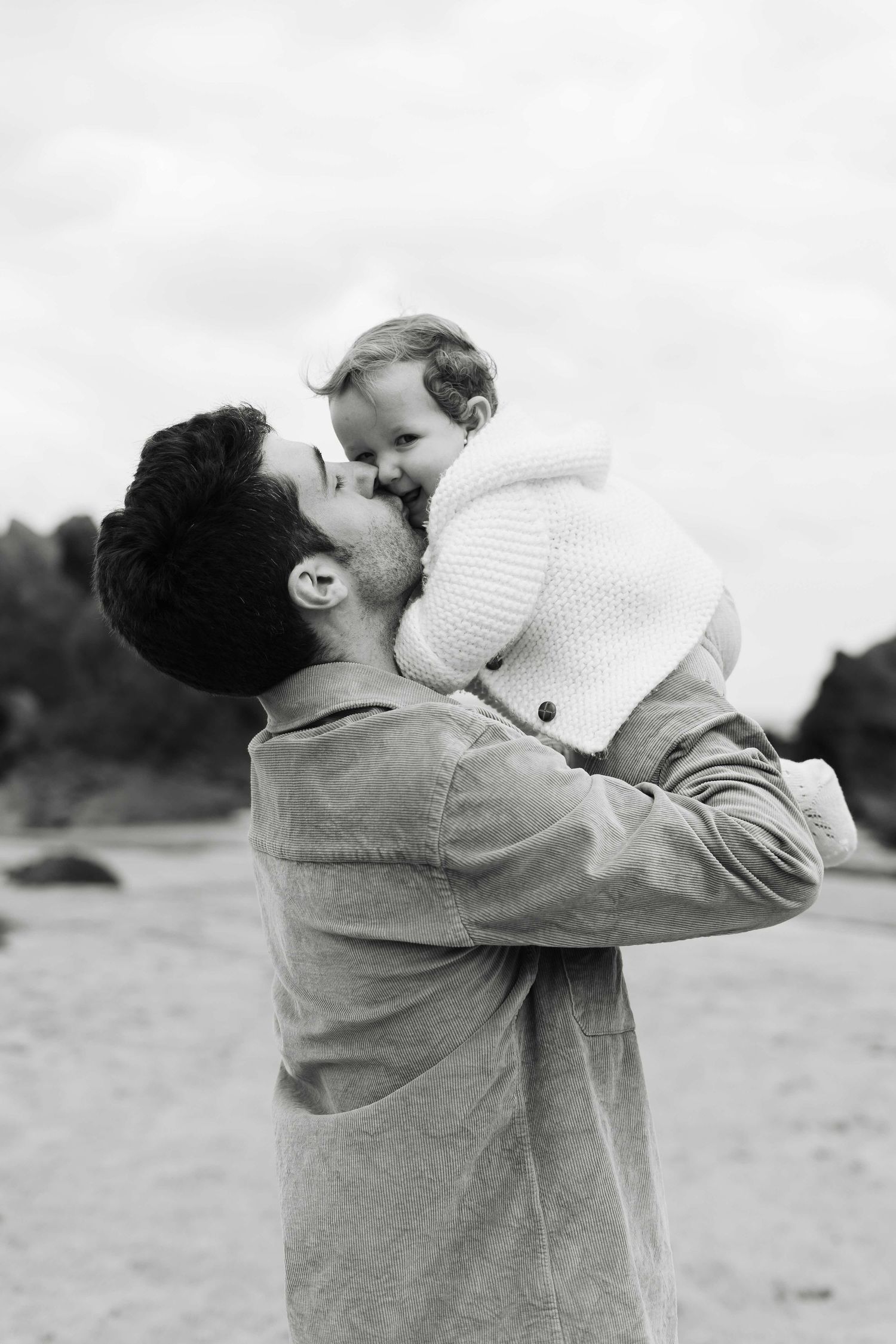 A tender moment between parent and child as they embrace outdoors in black and white photography.