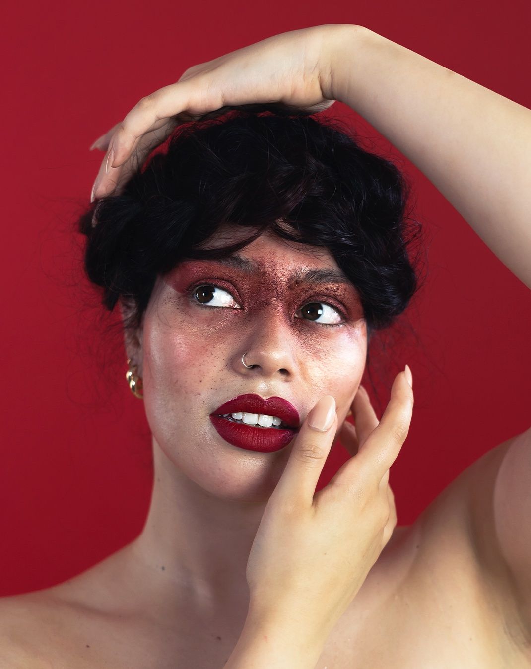 Artistic portrait series against a red background featuring dramatic makeup and poses.