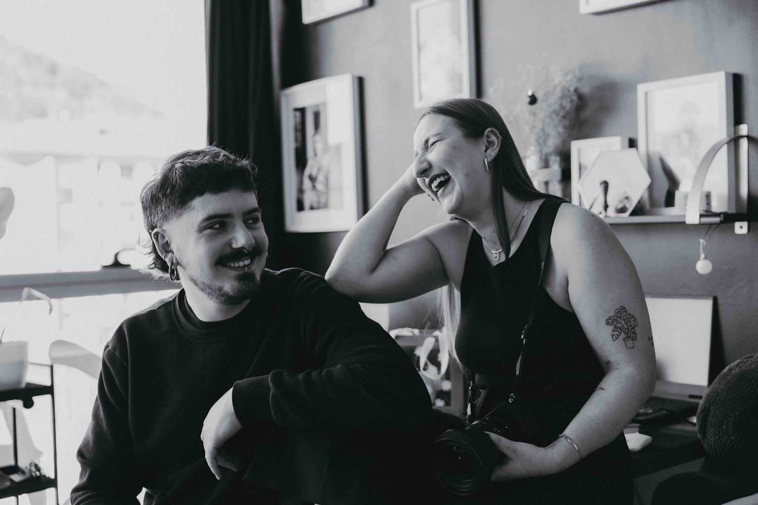 Couple shares joyful moment in casual indoor setting with natural expressions.