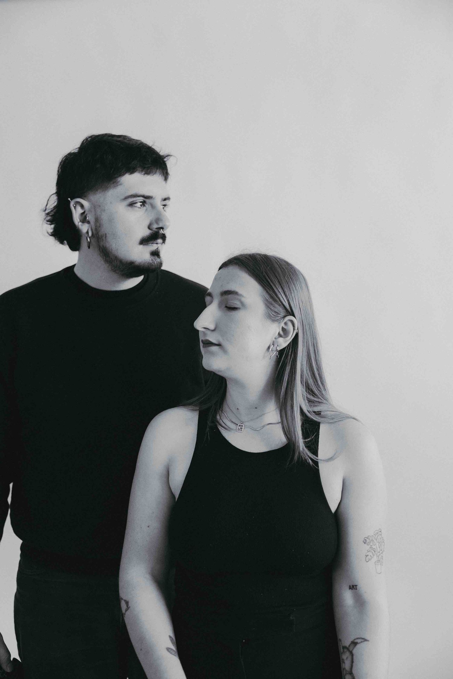 Intimate black and white portrait captures couple's connection in minimalist studio setting.