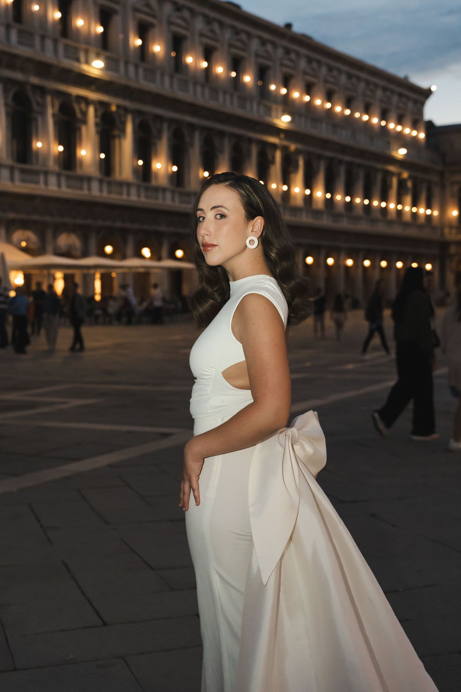 Evening fashion shoot at St Mark's Square with illuminated arcades and white gown.