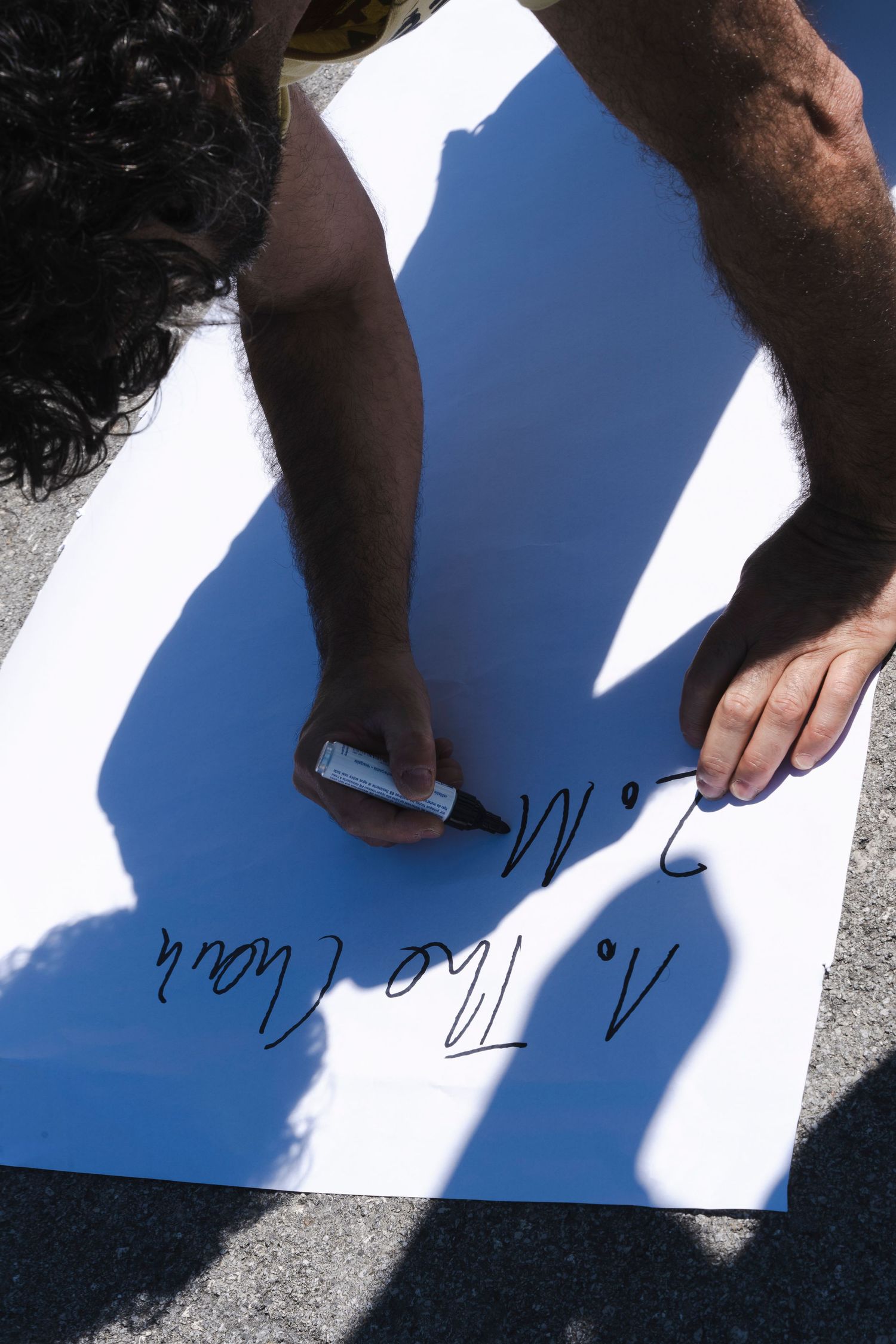 Shadow of person signing document on white paper in bright sunlight.