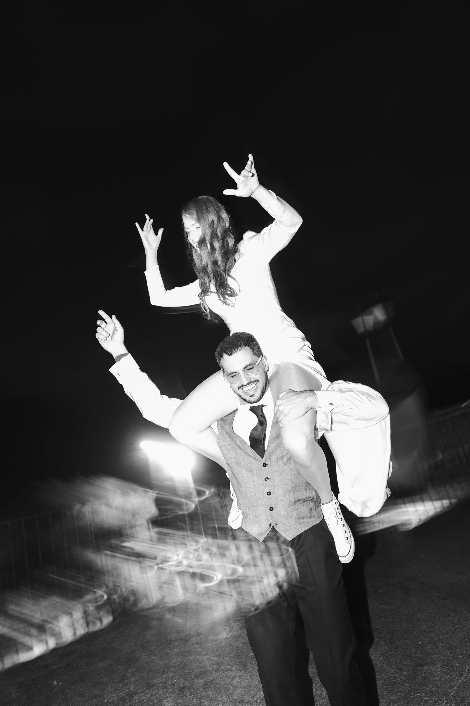 Black and white photo of couple having fun with playful lift during wedding reception.