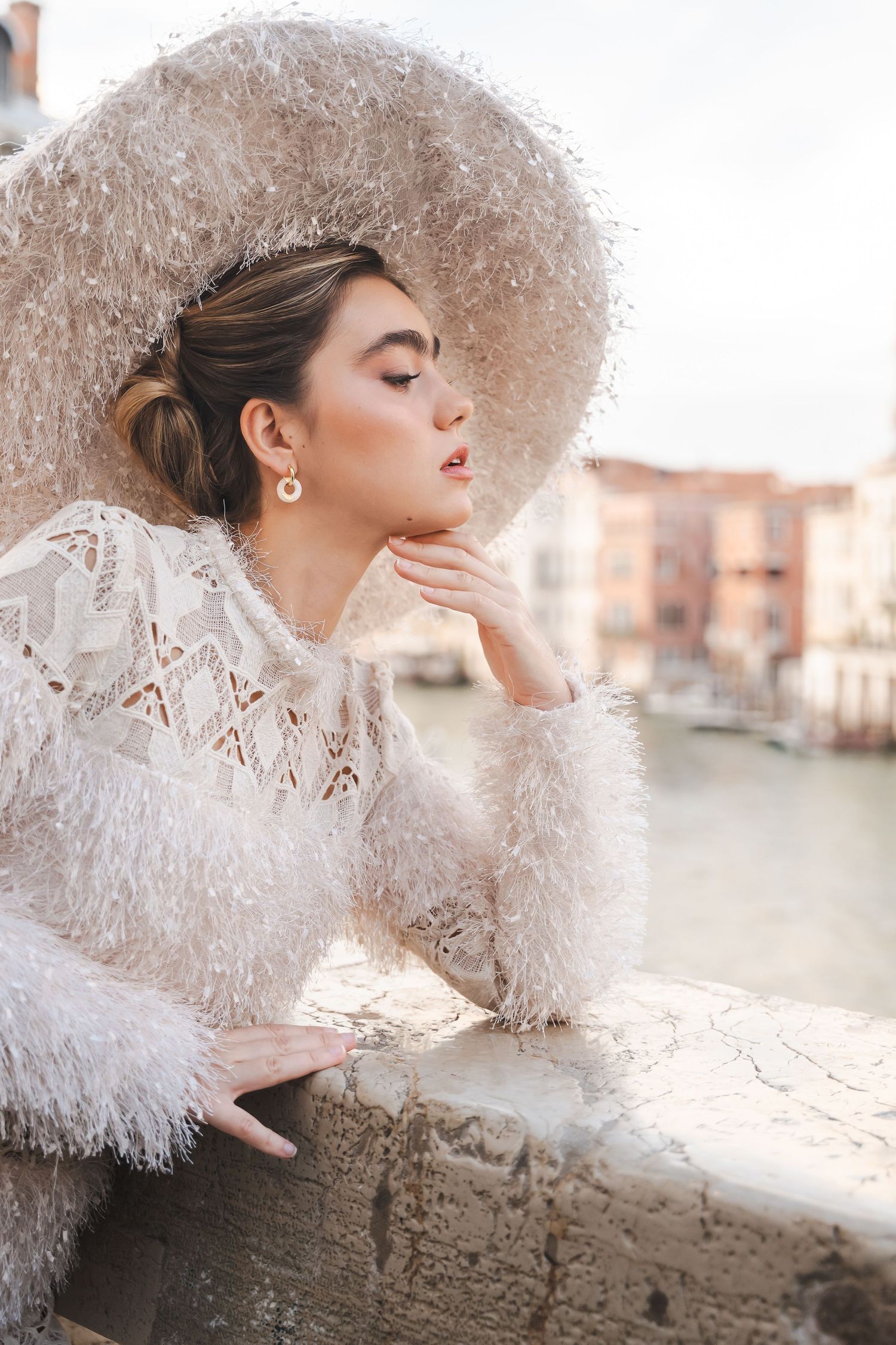 Romantic portrait series featuring white feathered dress against Venice canal backdrop.