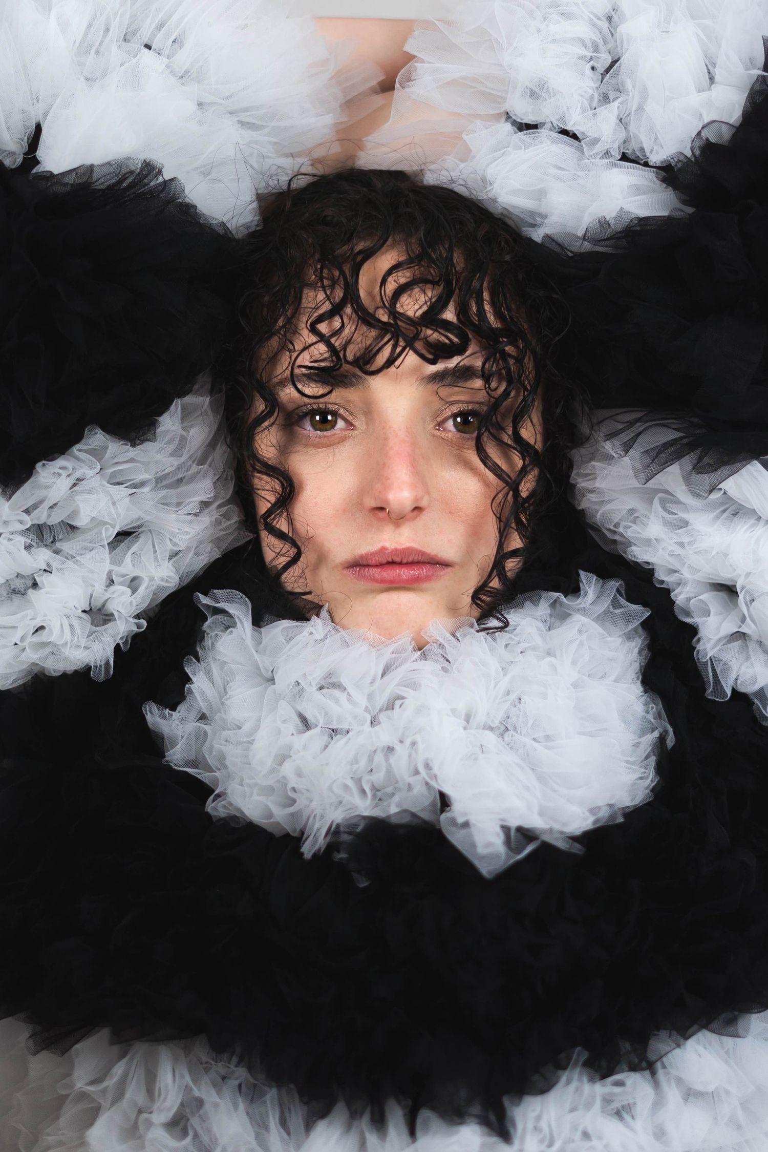 Artistic portrait surrounded by white feathers against dark background.