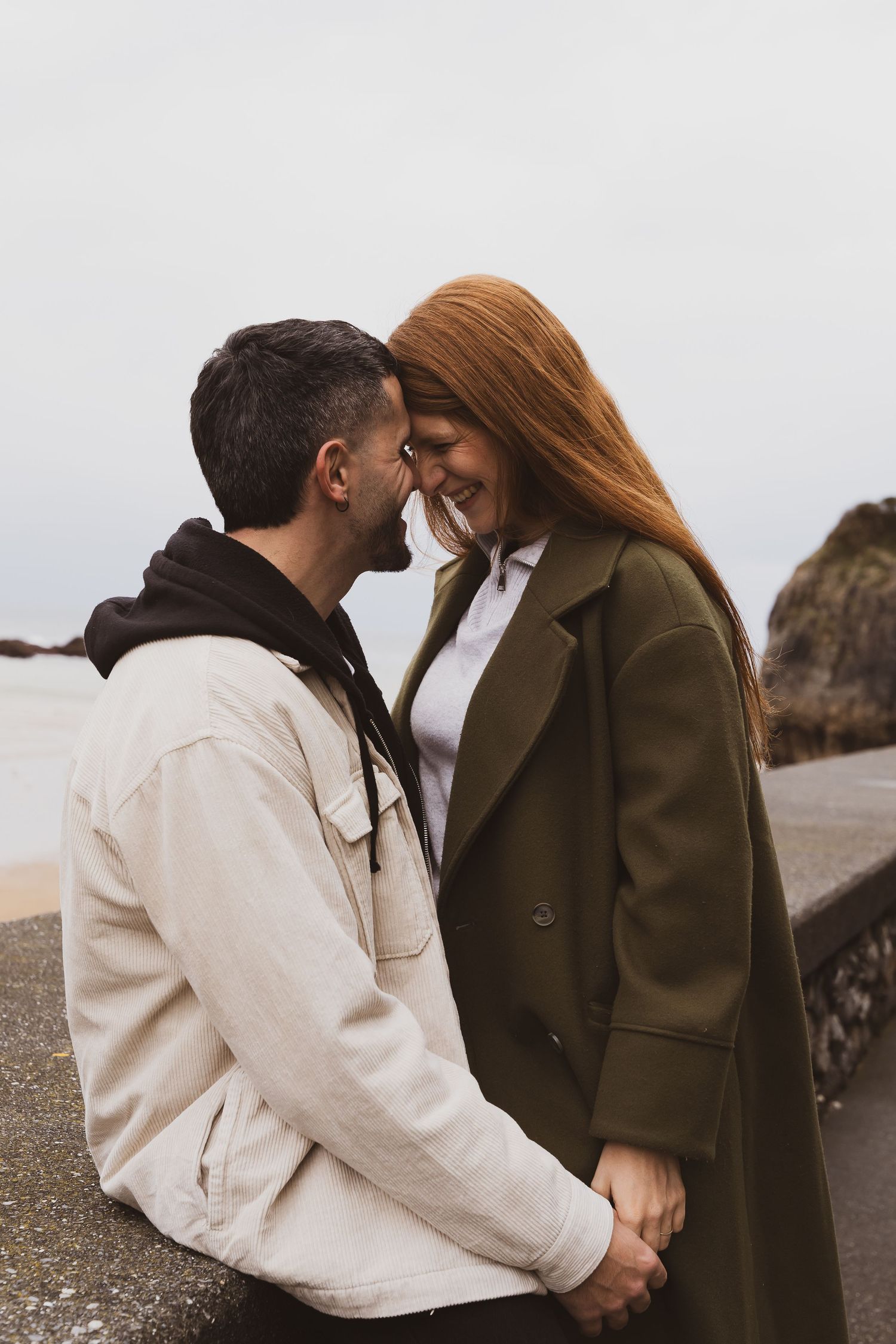 A romantic couple sharing an intimate moment on a cloudy beach.