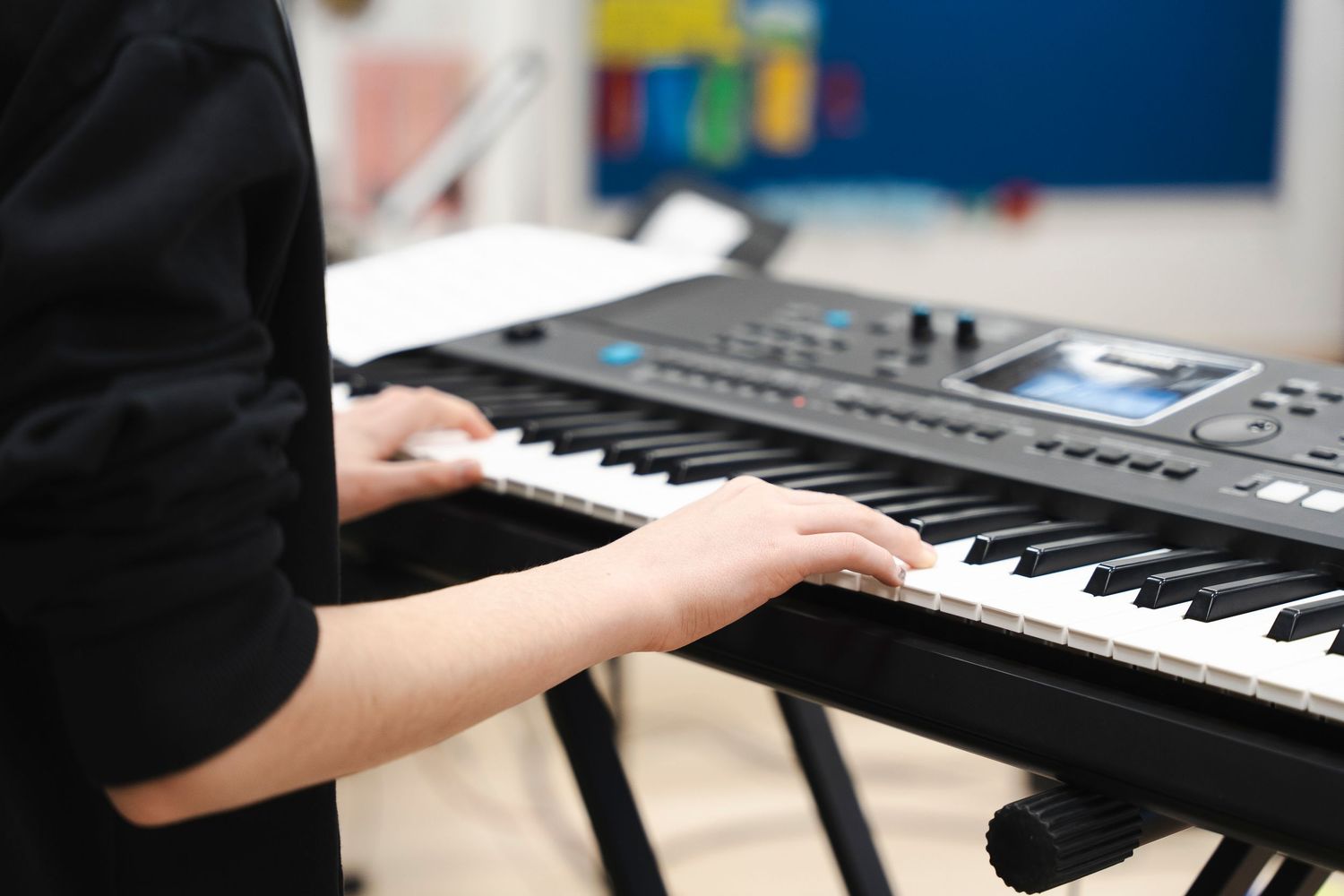 Close-up of hands playing digital keyboard piano in studio setting.