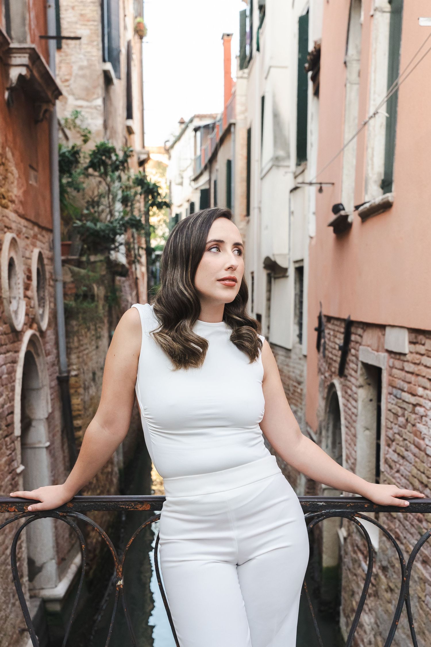 Street fashion photography in Venice featuring white outfit against pink stone walls.