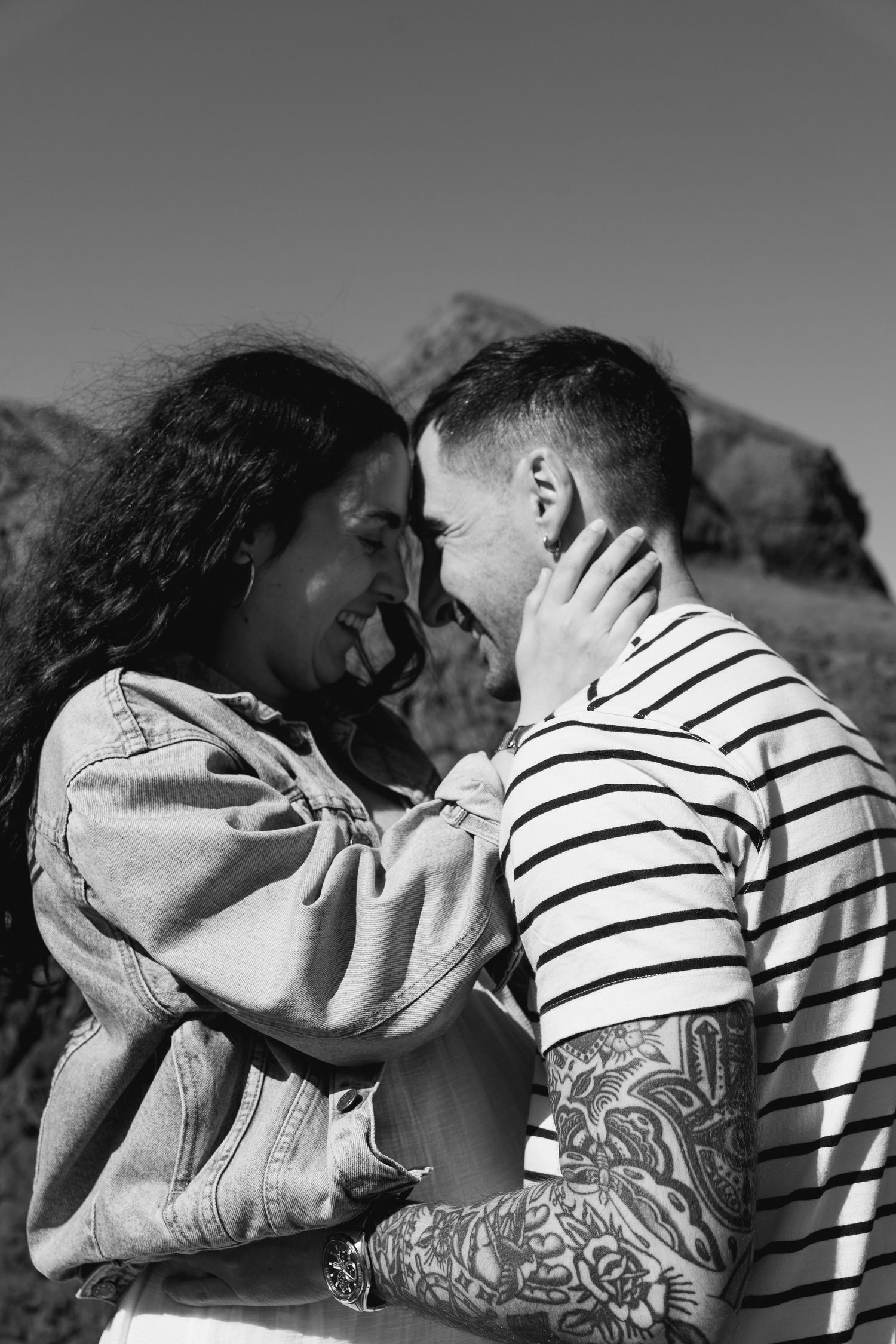Couple sharing an intimate moment against a mountainous backdrop.