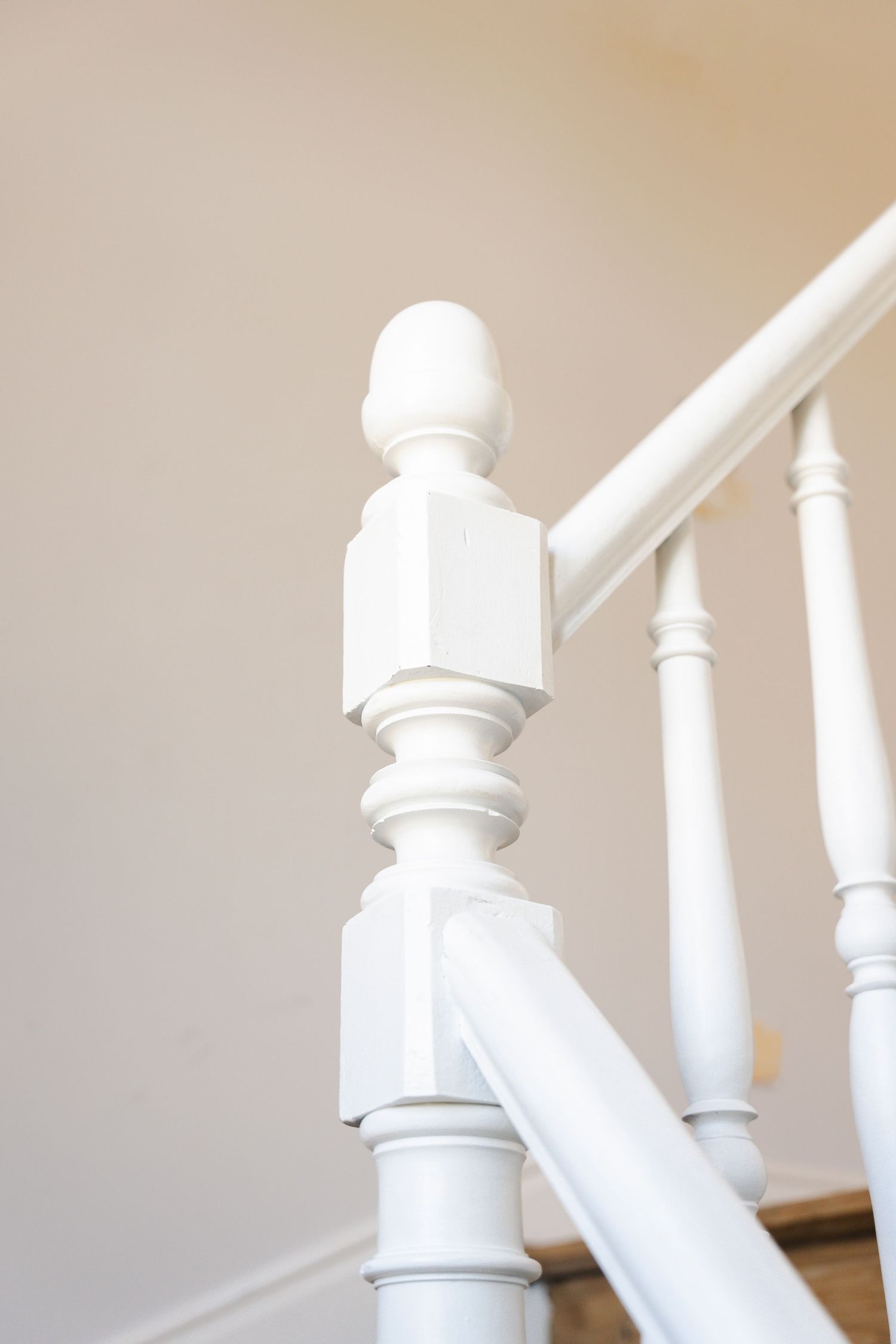 Close-up of white painted wooden staircase banister post with classic detailing.