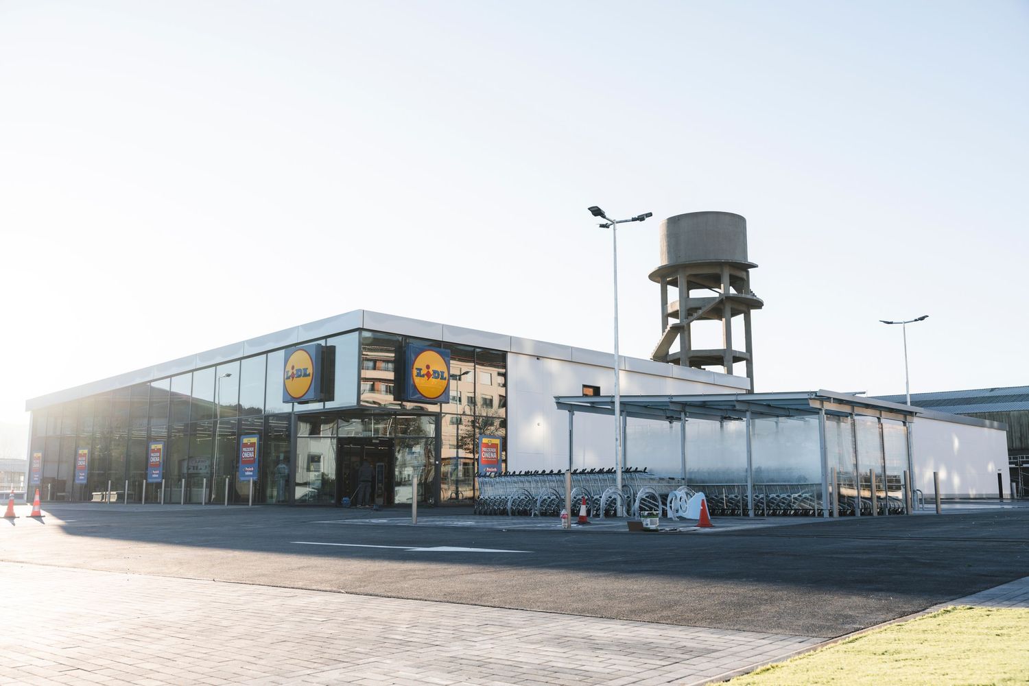 Modern convenience store exterior with glass windows and water tower in daylight.