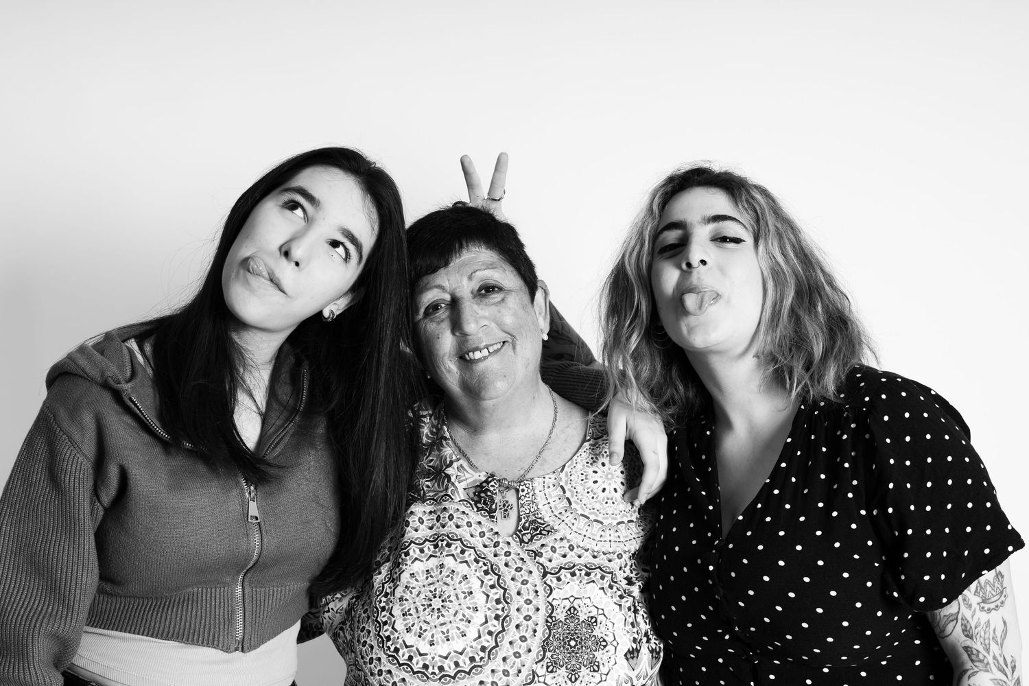Three people making silly faces and bunny ears pose together for a fun black and white portrait.