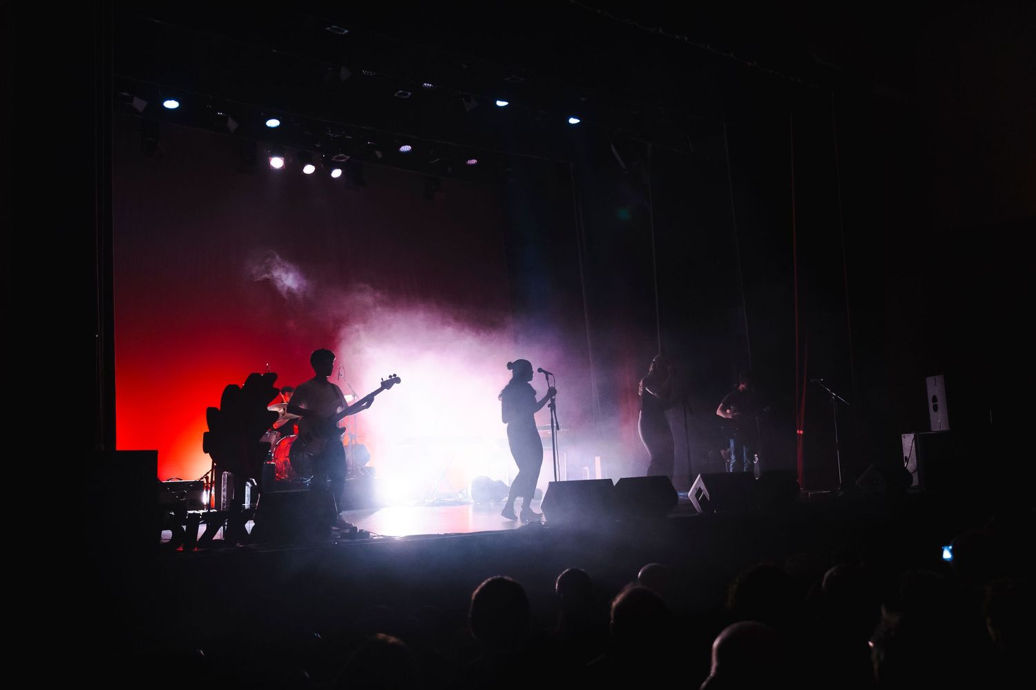 Silhouetted band performing on stage with dramatic red and white lighting effects.