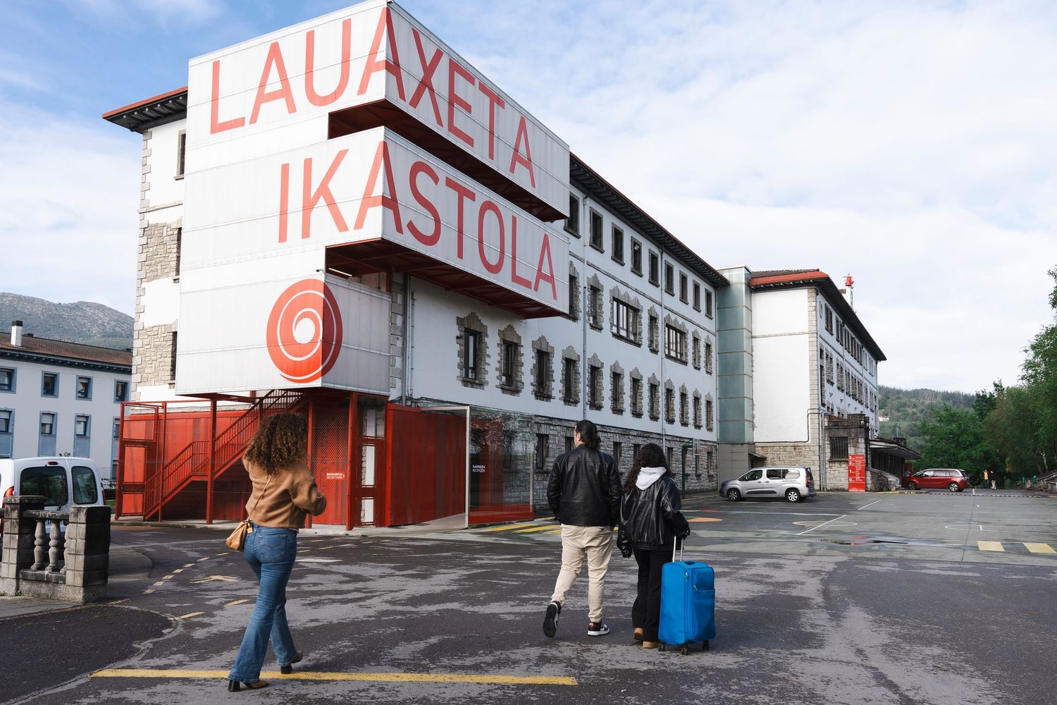 Large white building with red text reading Lauaxeta Ikastola against blue sky.