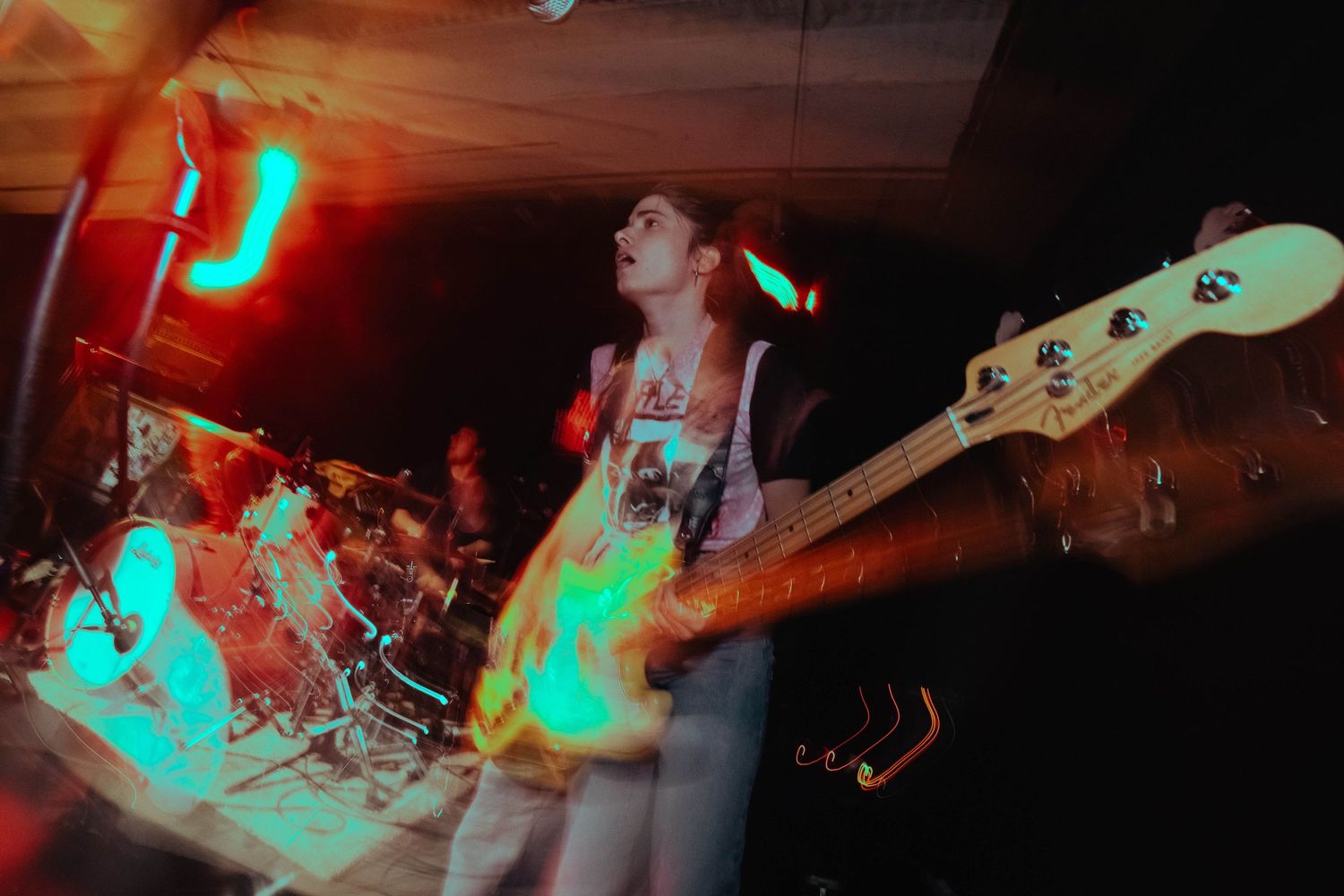 Bass player performing on stage with colorful neon lights in a dynamic concert atmosphere.