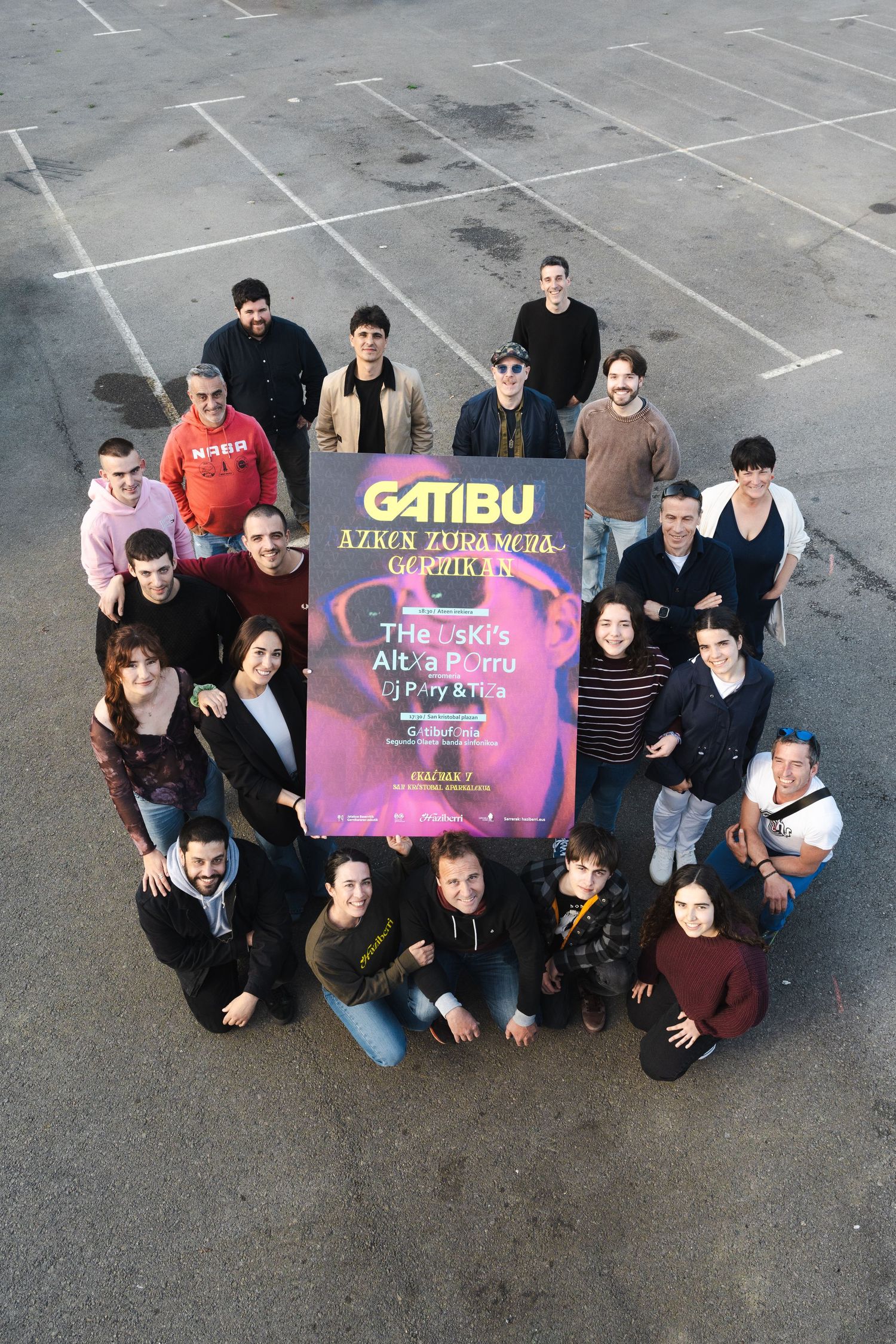Group photo of students posing with colorful event posters on asphalt ground.
