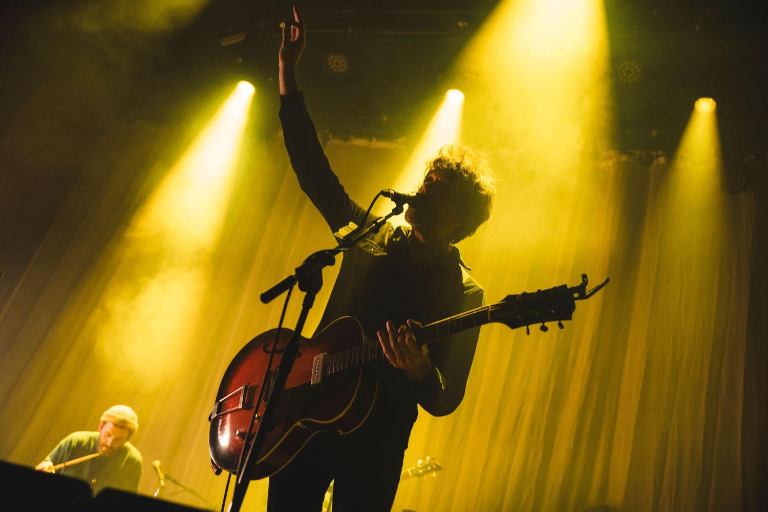 Silhouetted musician performing on stage under dramatic yellow spotlights.