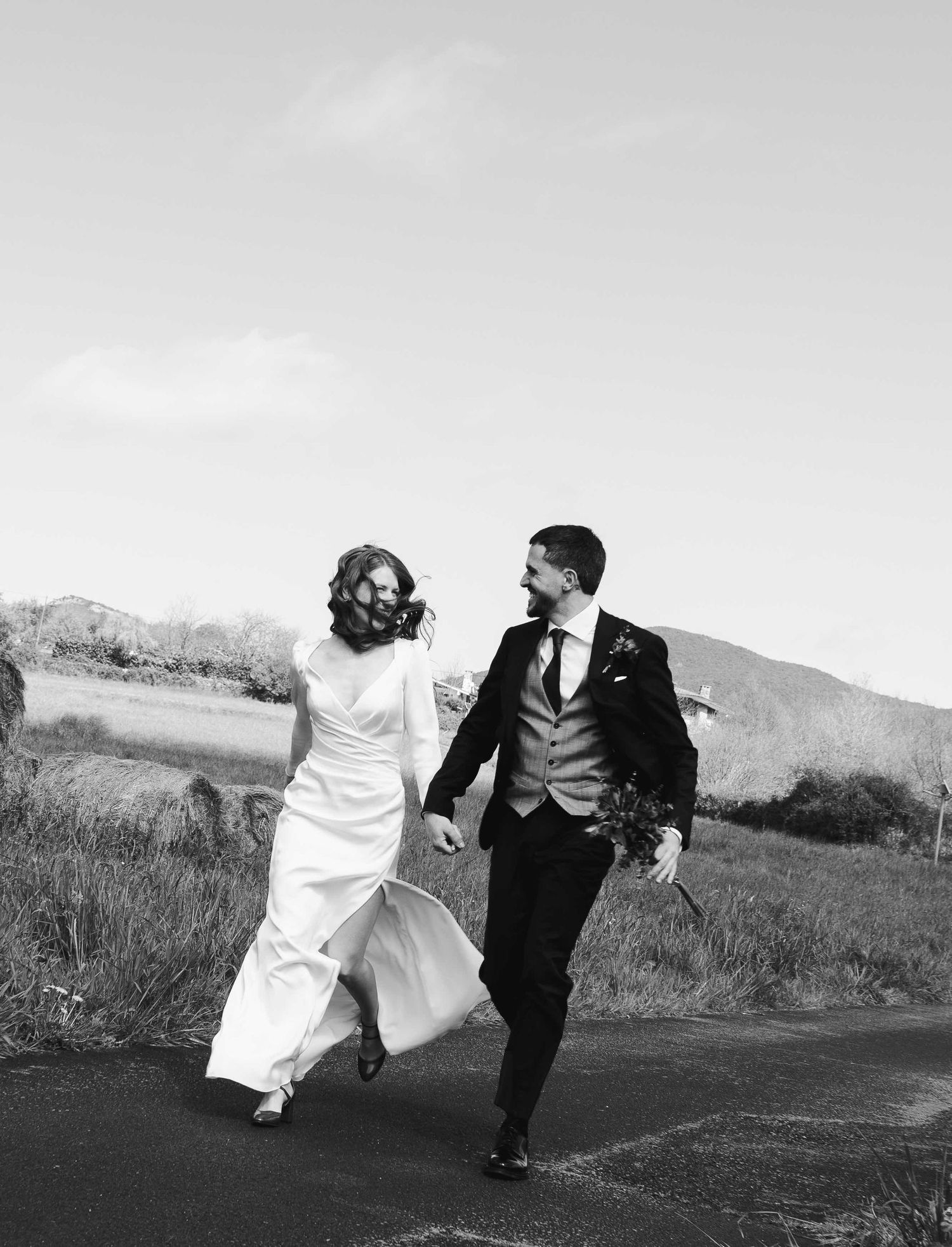 Series of playful black and white photos showing a couple running together in a field.