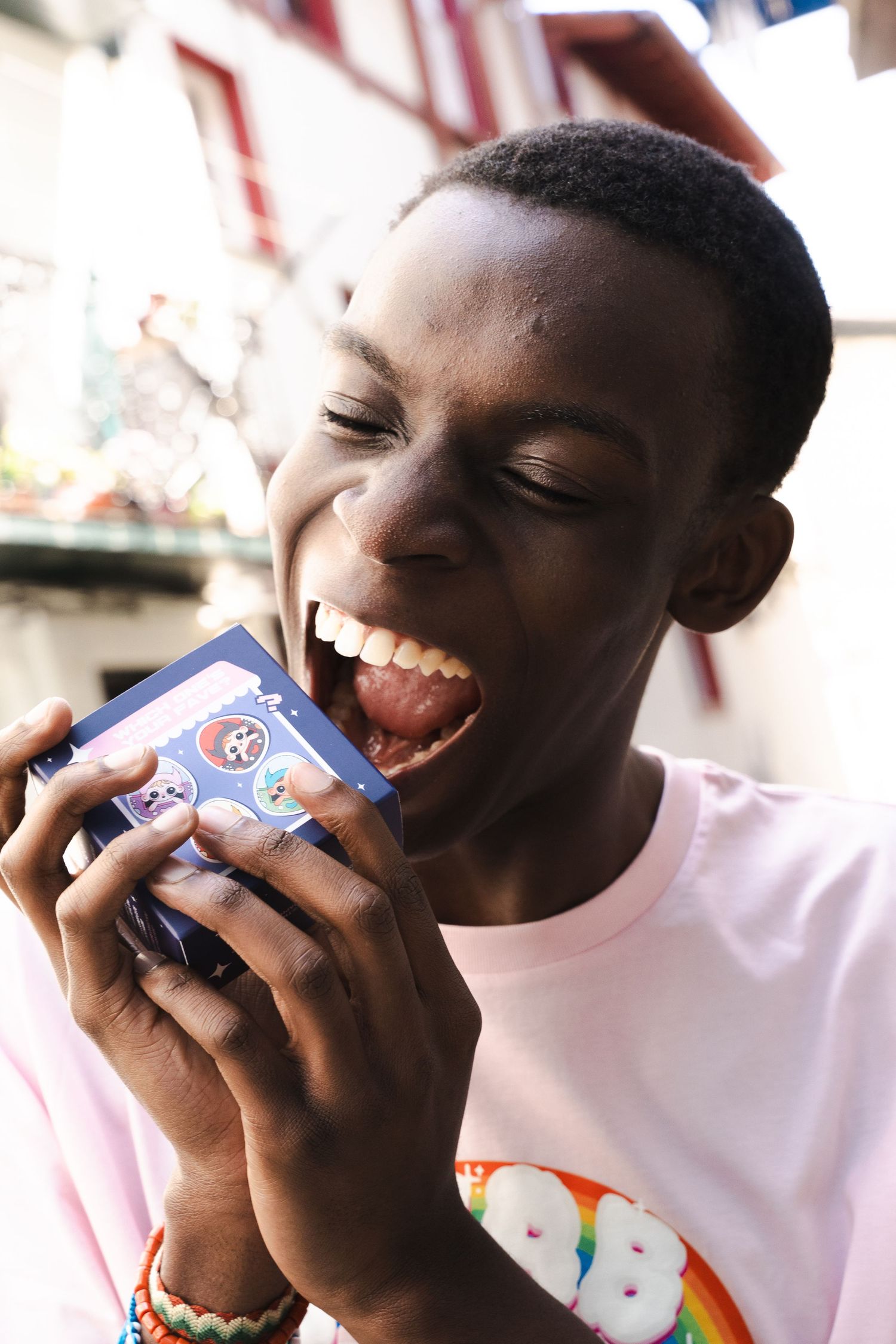 Person in pink t-shirt joyfully biting into a snack with cartoon character packaging.