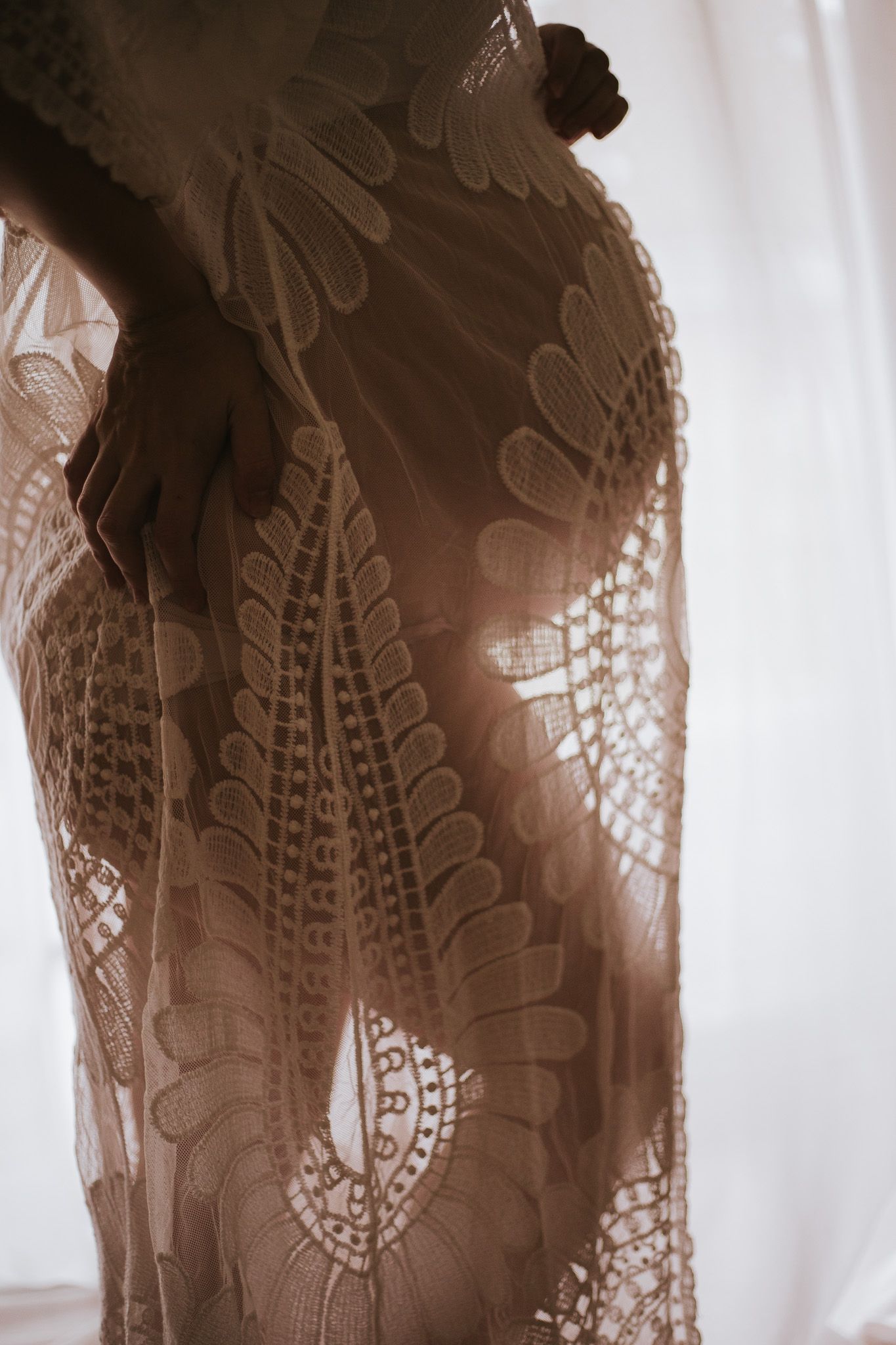 Close-up detail of brown lace fabric with intricate floral and paisley patterns against a light background.