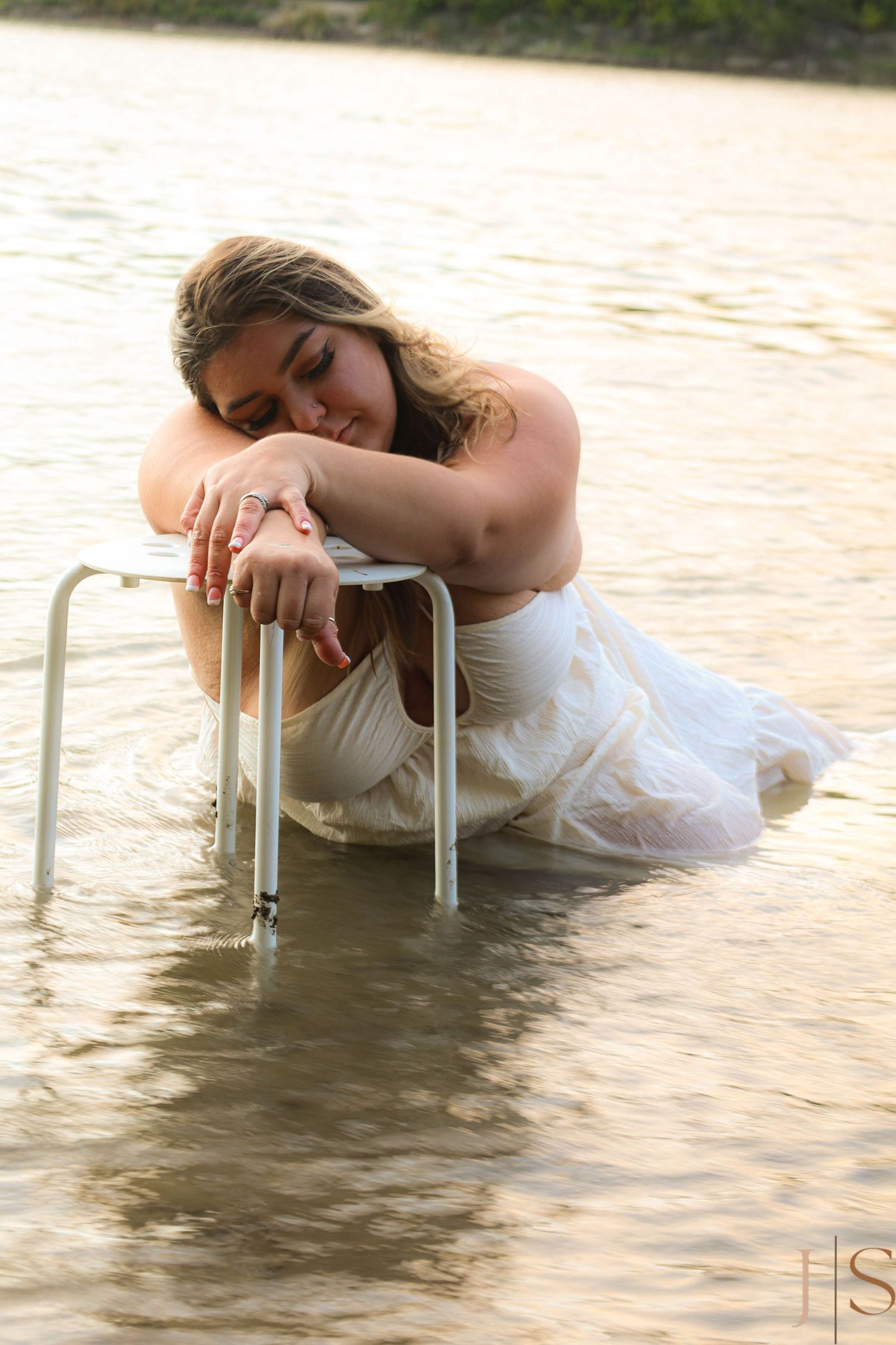 Artistic portrait in water showing white dress and ladder creating ethereal effect.