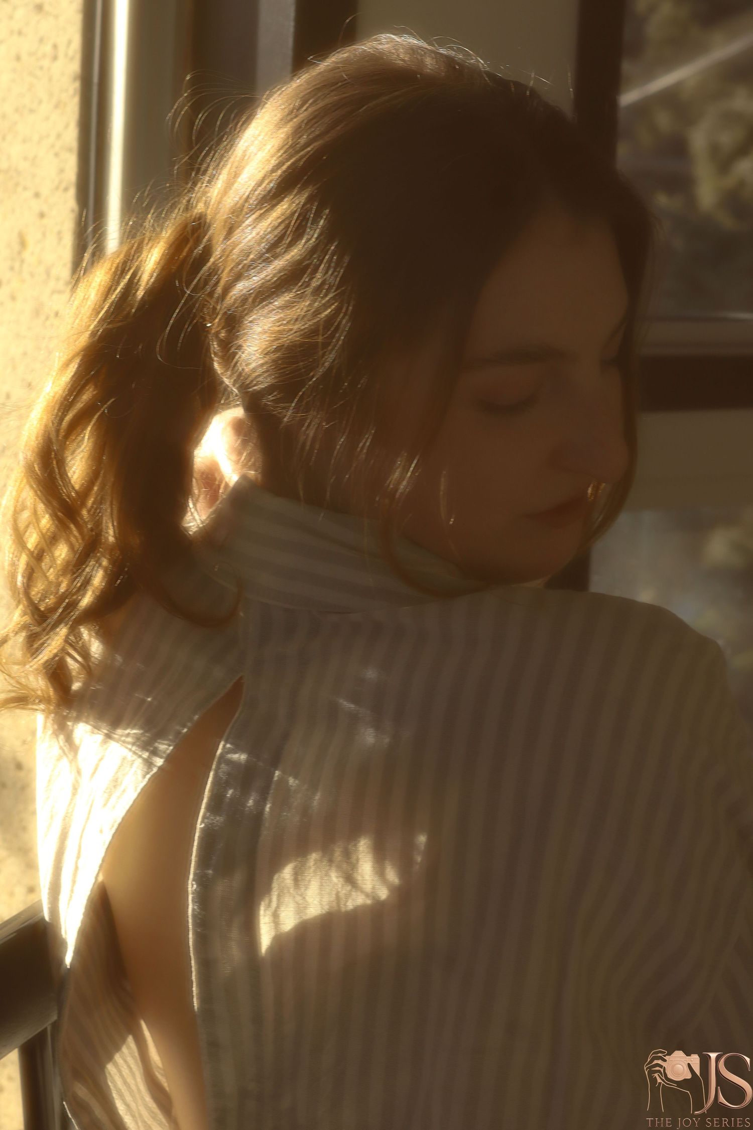 Warm sunlit portrait with golden backlighting creating a dreamy atmospheric glow through a turtleneck sweater.