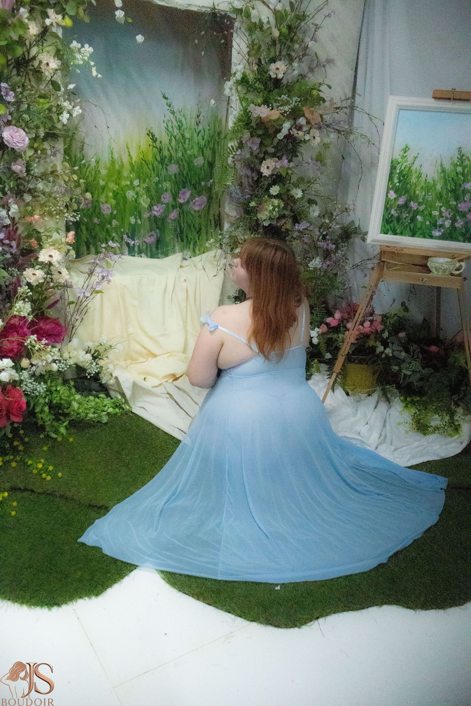 Ethereal garden scene with flowing blue dress among white flowers and greenery.