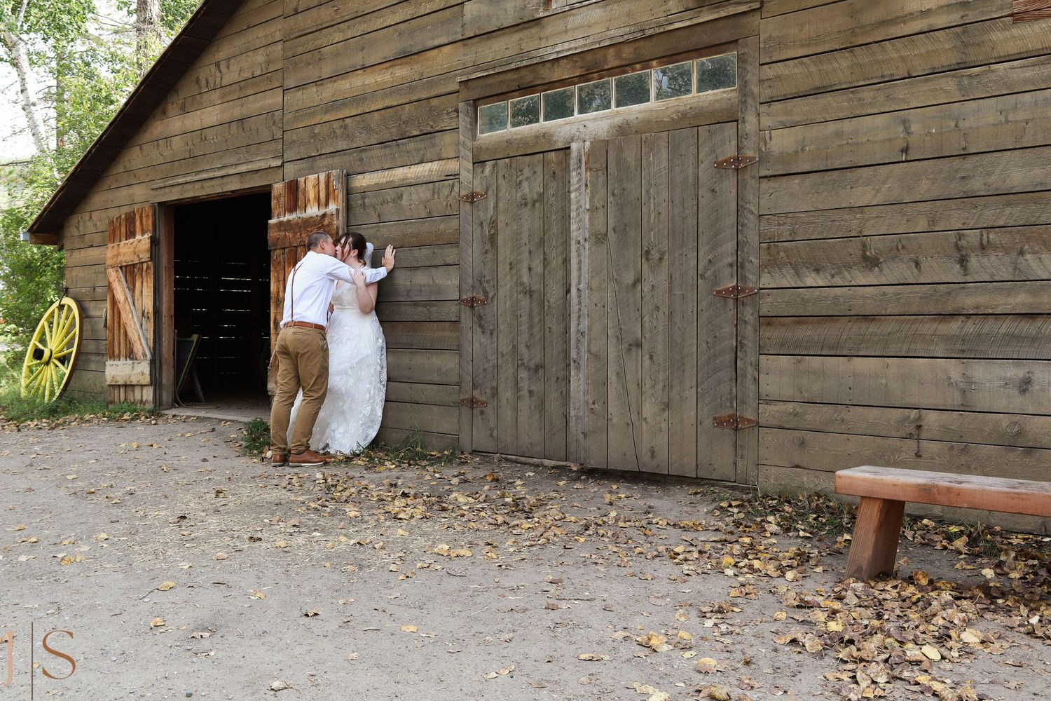 Rustic wooden barn structure with weathered boards and multiple doorways in a rural setting.