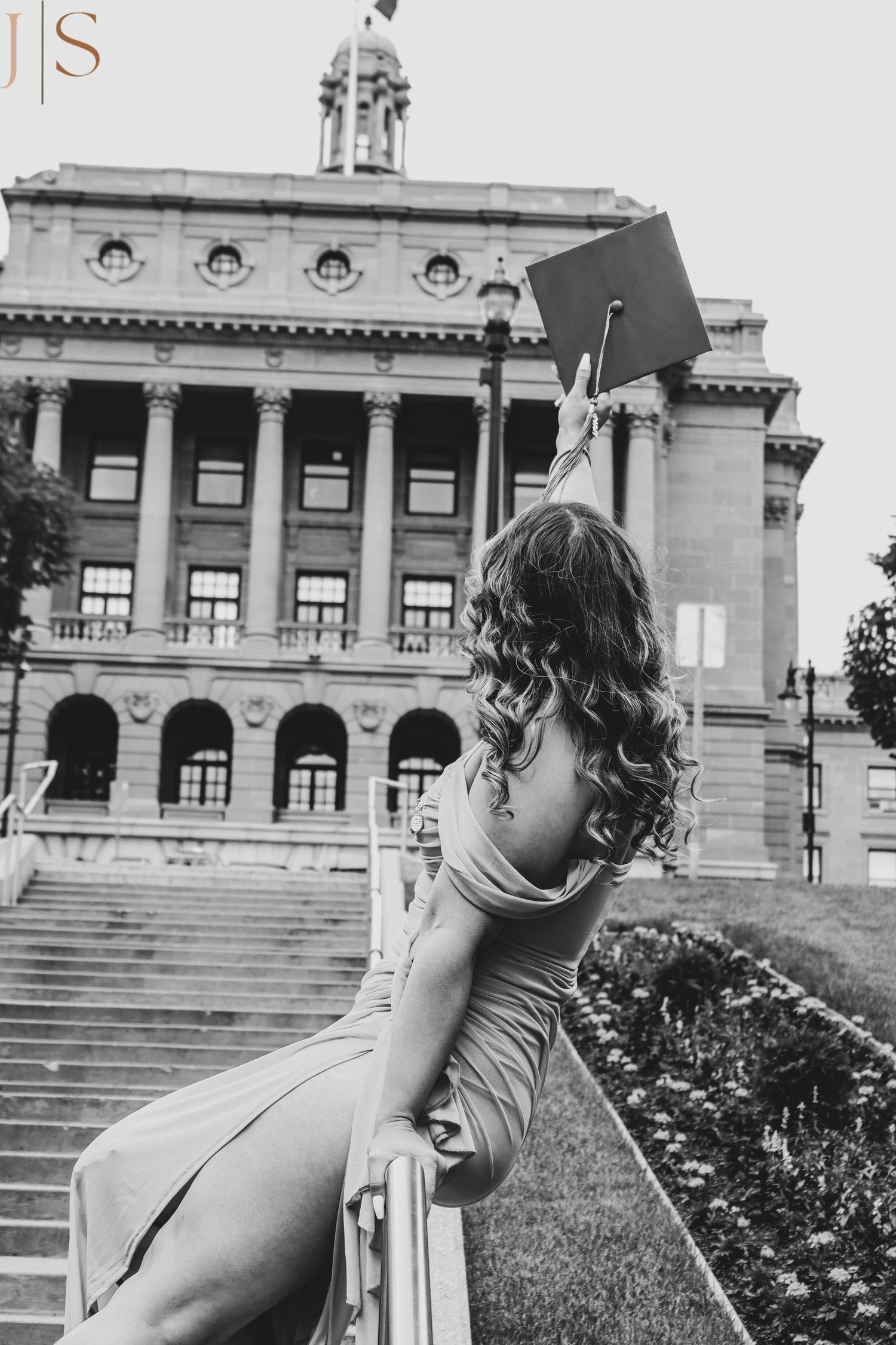 Person sitting on the steps of a grand historic building with classical architecture and columns.