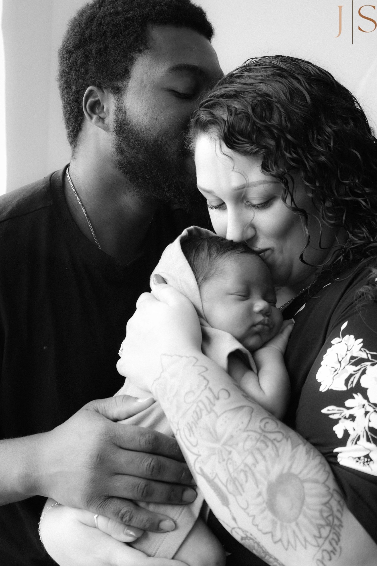 A series of intimate black and white photographs showing tender family moments between parents and their newborn baby.