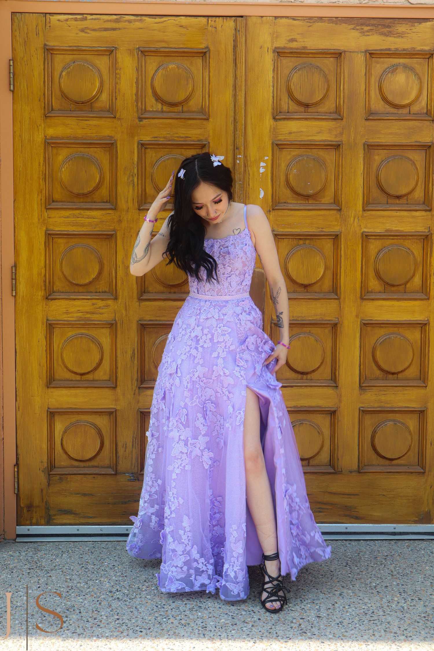 Elegant formal dress photoshoot featuring a lavender lace gown against ornate wooden doors.