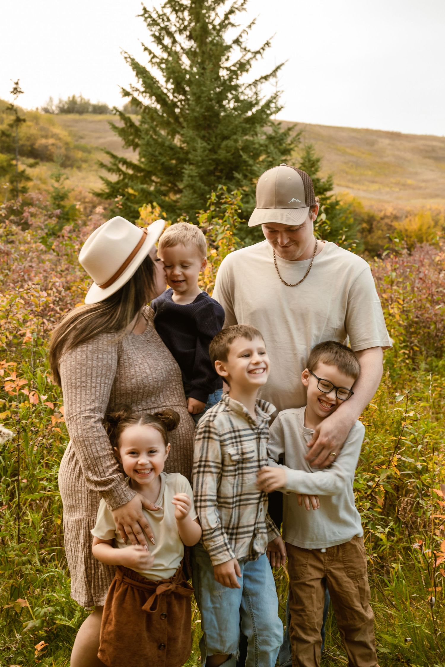 Family shares joyful moments together in a wildflower meadow during golden hour sunset.