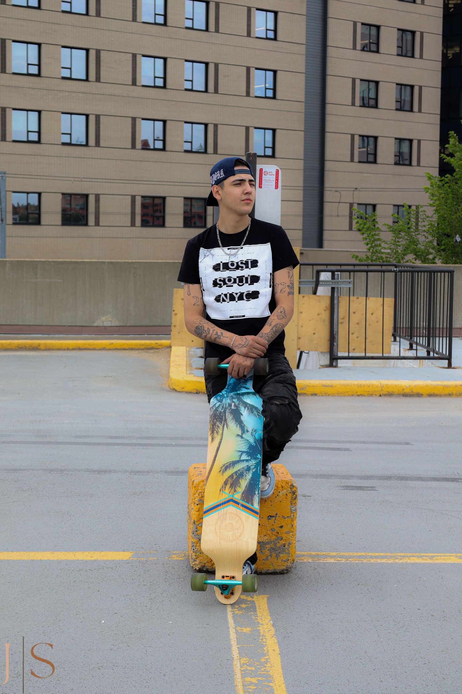 A series of images showing a skater sitting on a yellow bollard in a parking lot wearing a black t-shirt.