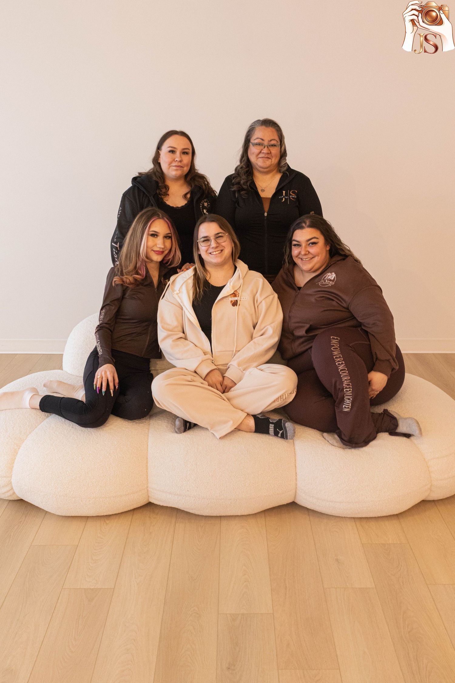 A group sits together on white bean bag chairs wearing casual loungewear in brown and beige tones.
