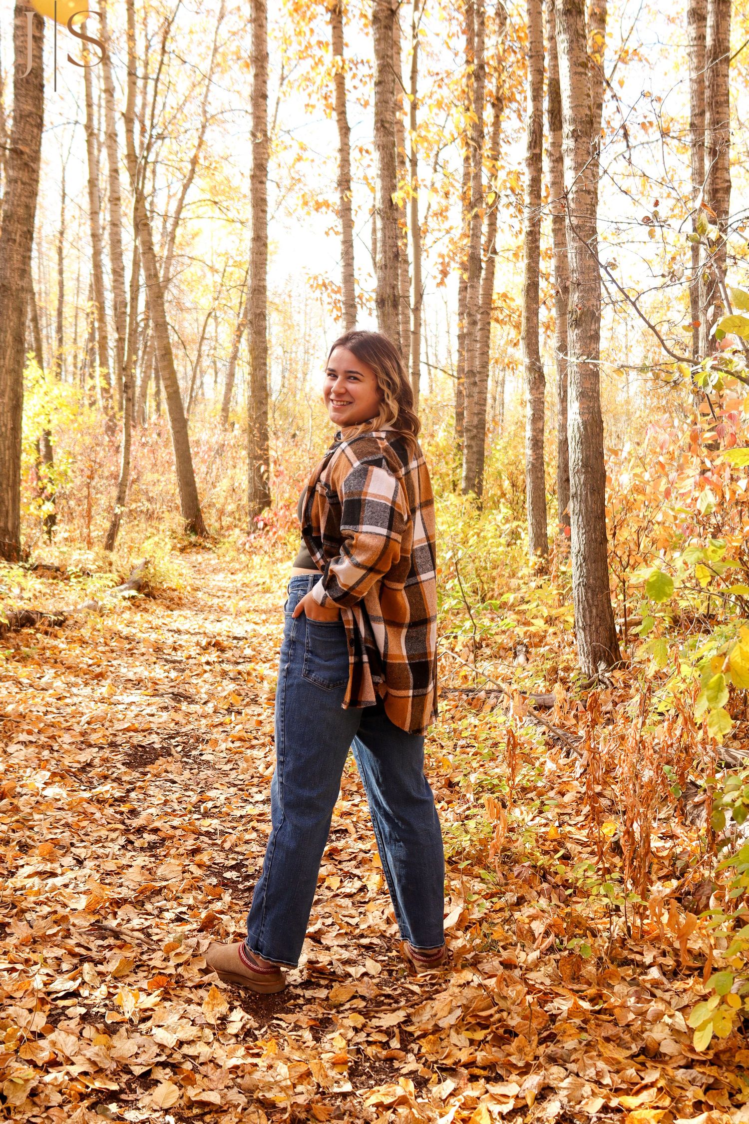 Autumn fashion photography in a forest with fallen leaves and plaid patterns.