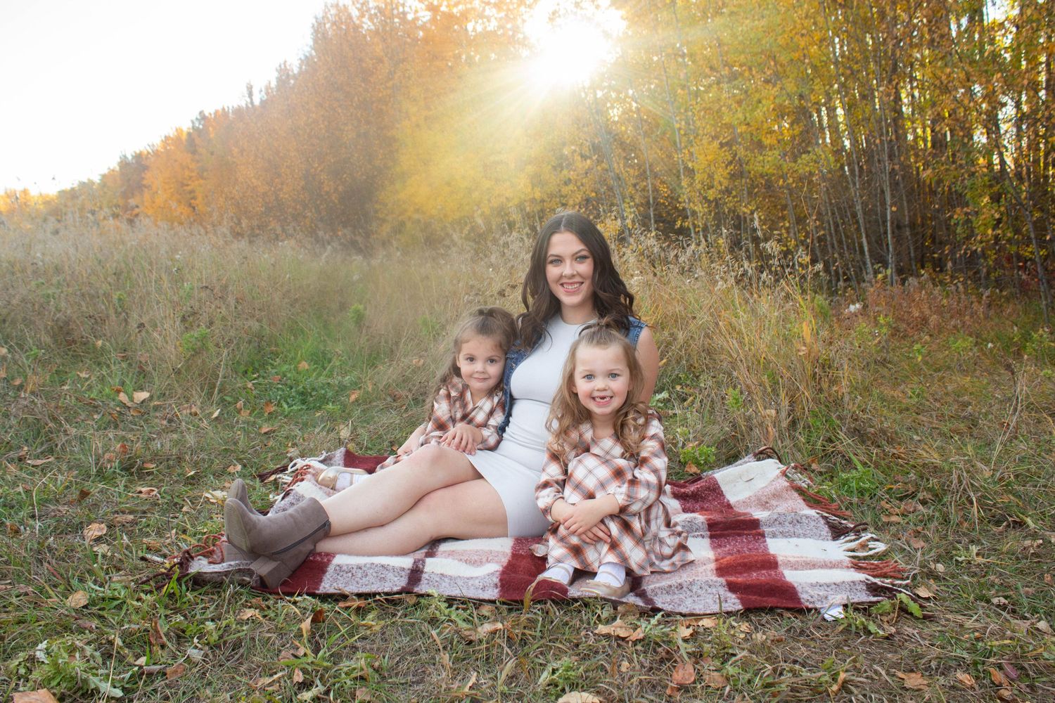 Family portrait on picnic blanket surrounded by golden fall foliage.
