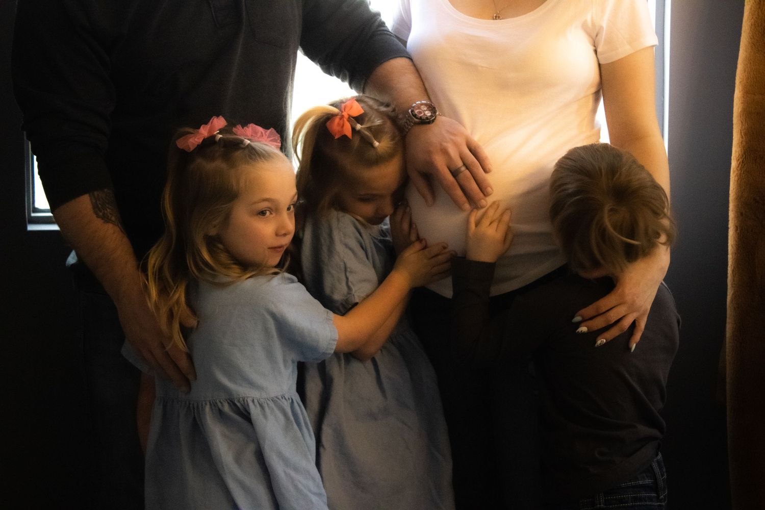 Children gather around their parents in a warmly lit room, sharing tender family moments.