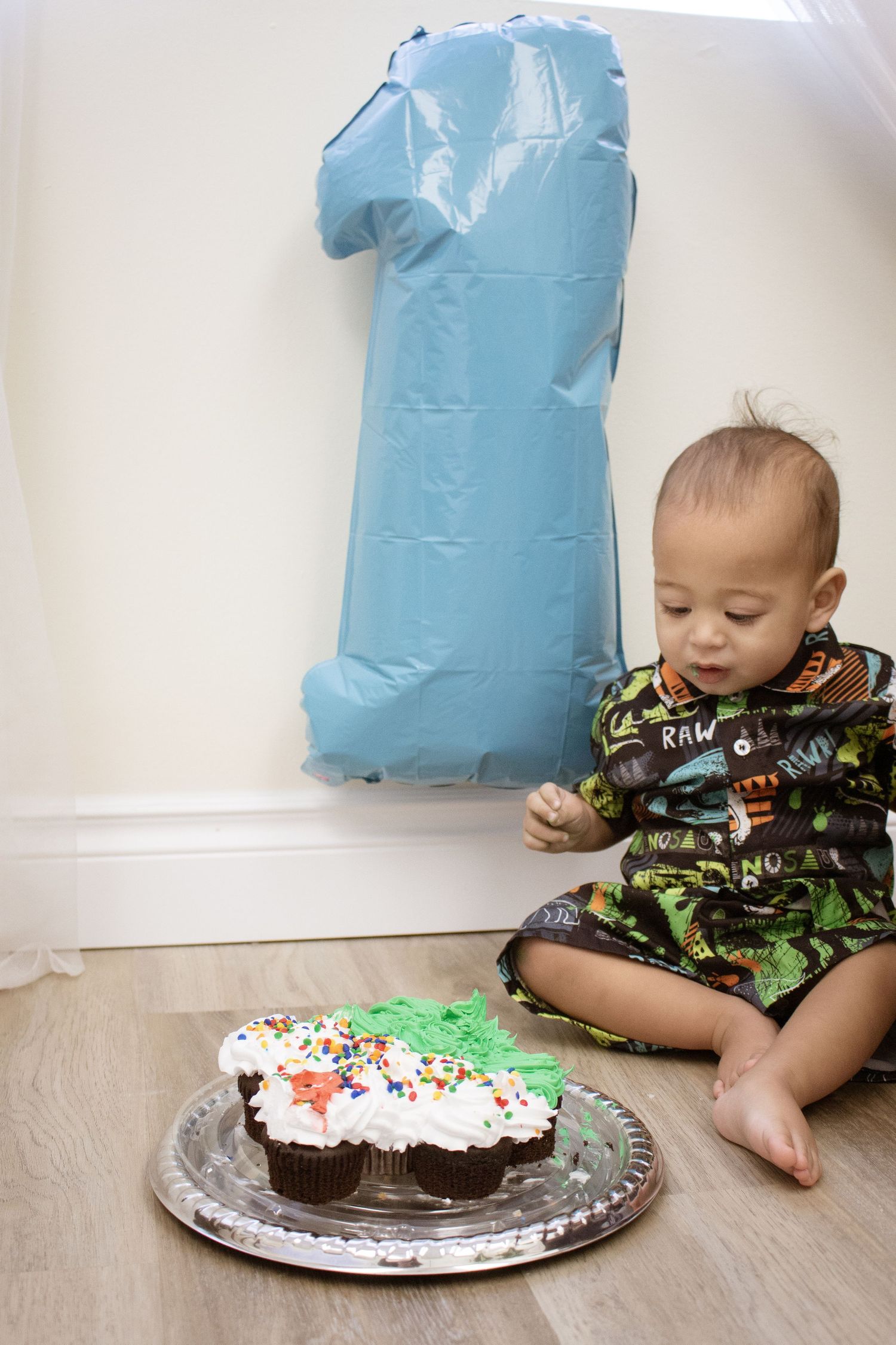 A celebration scene with a blue number one balloon and chocolate cake with sprinkles.