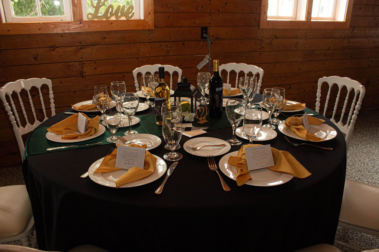 Elegant table setting with dark green tablecloth and gold accents at wedding reception.