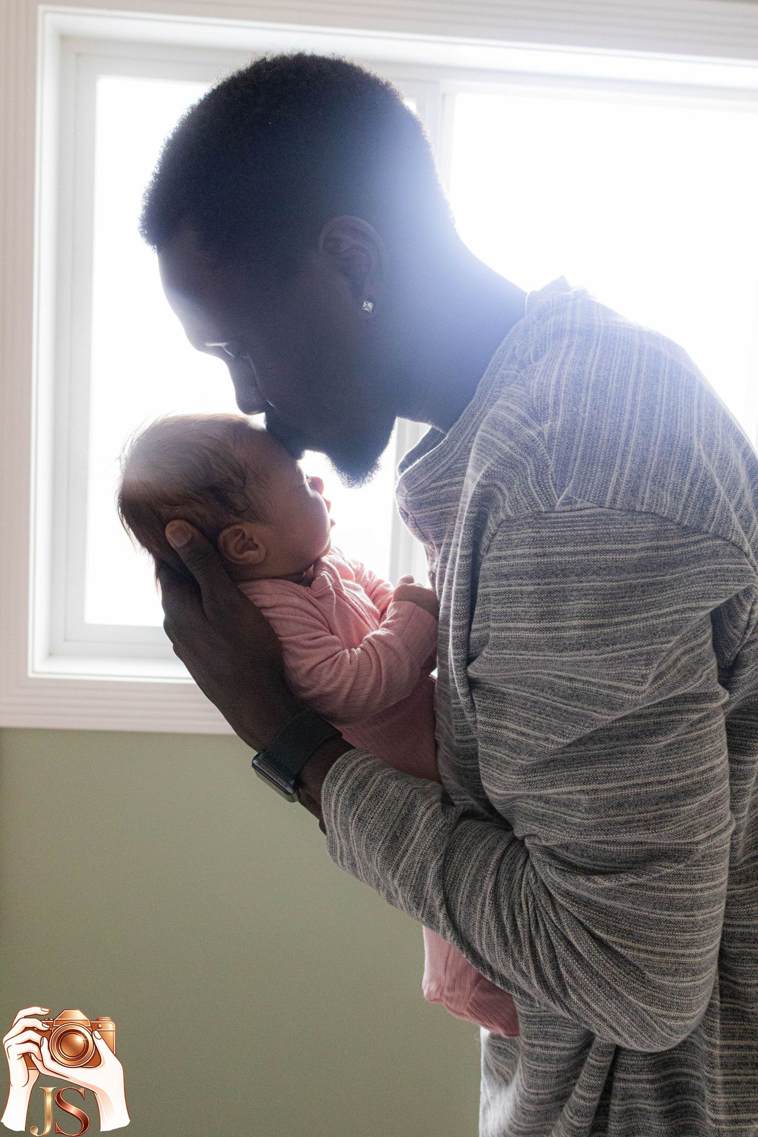 A series of silhouetted figures against bright windows showing tender moments with a small baby.