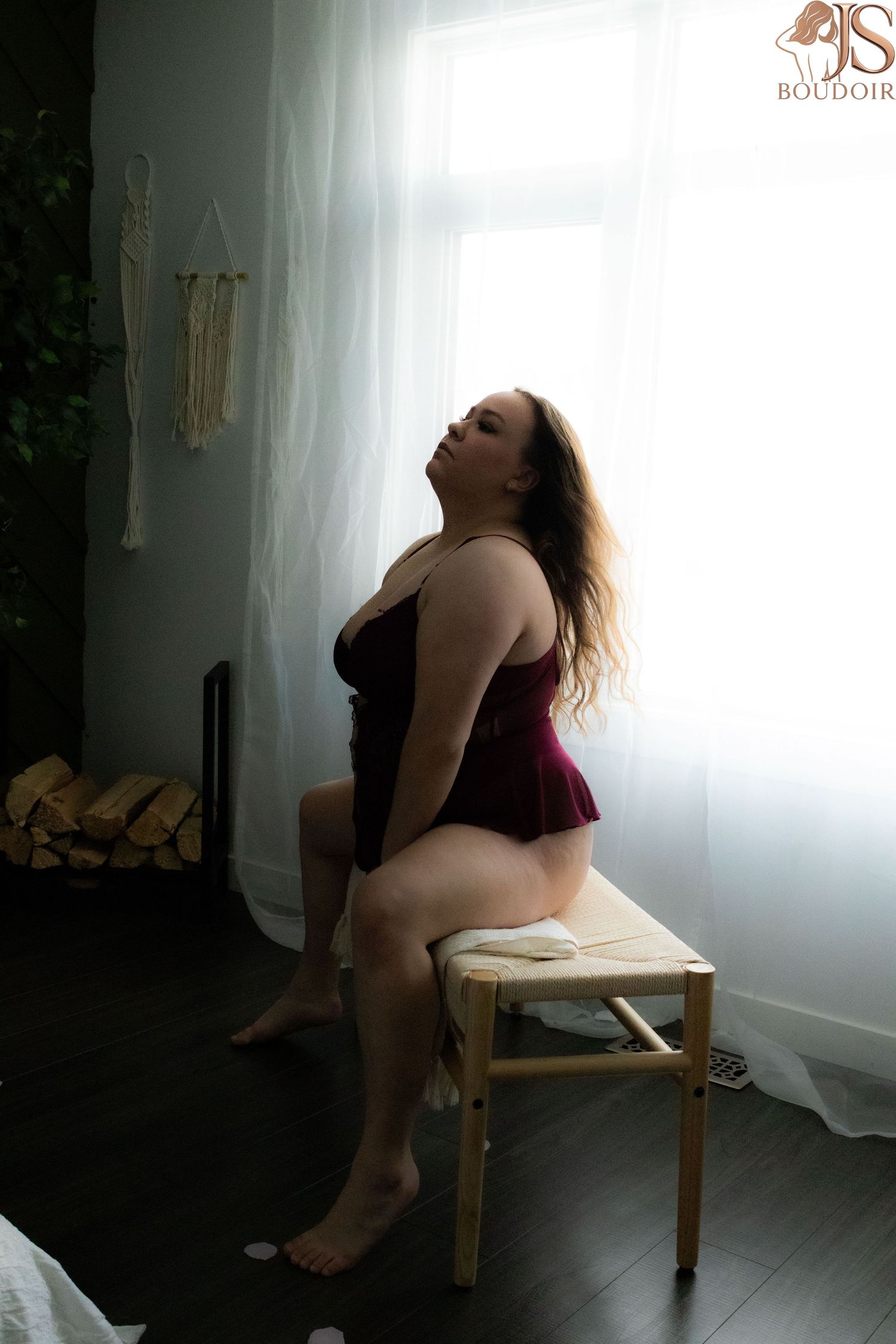 Artistic boudoir photography series showing a figure in burgundy lingerie posing on a wooden chair near a window.