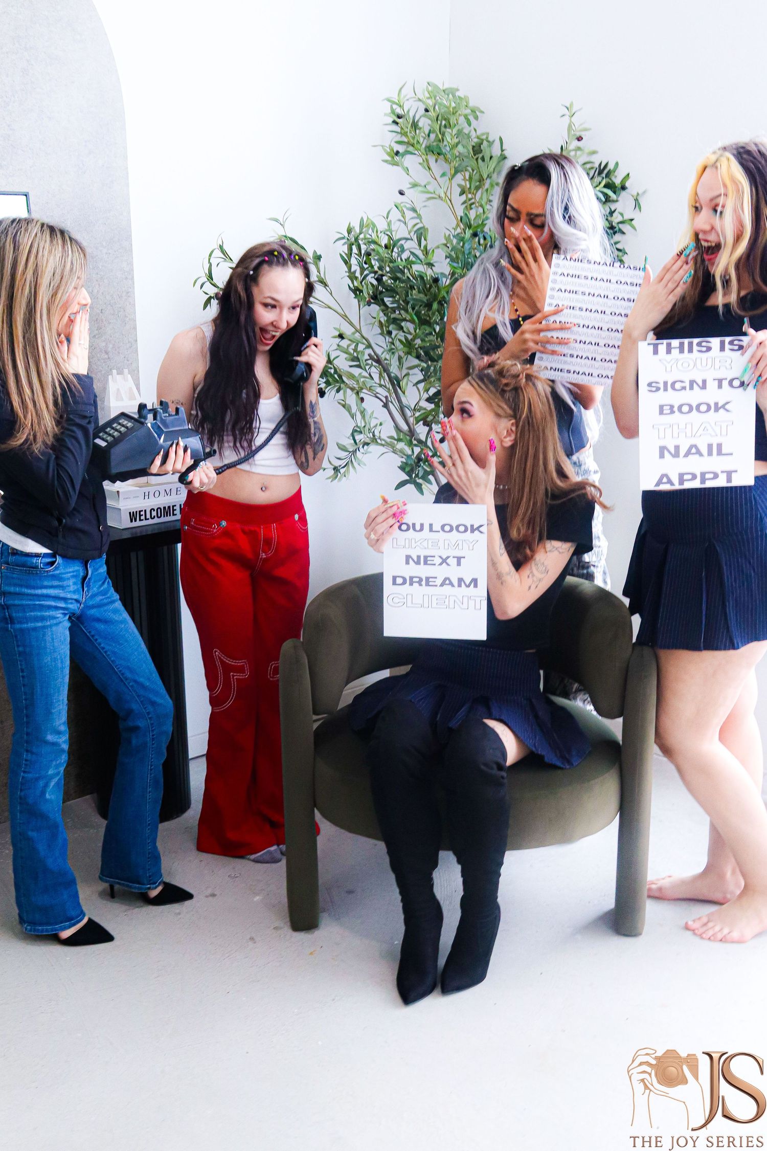 Group of friends holding up vision board signs and laughing together during a photoshoot.