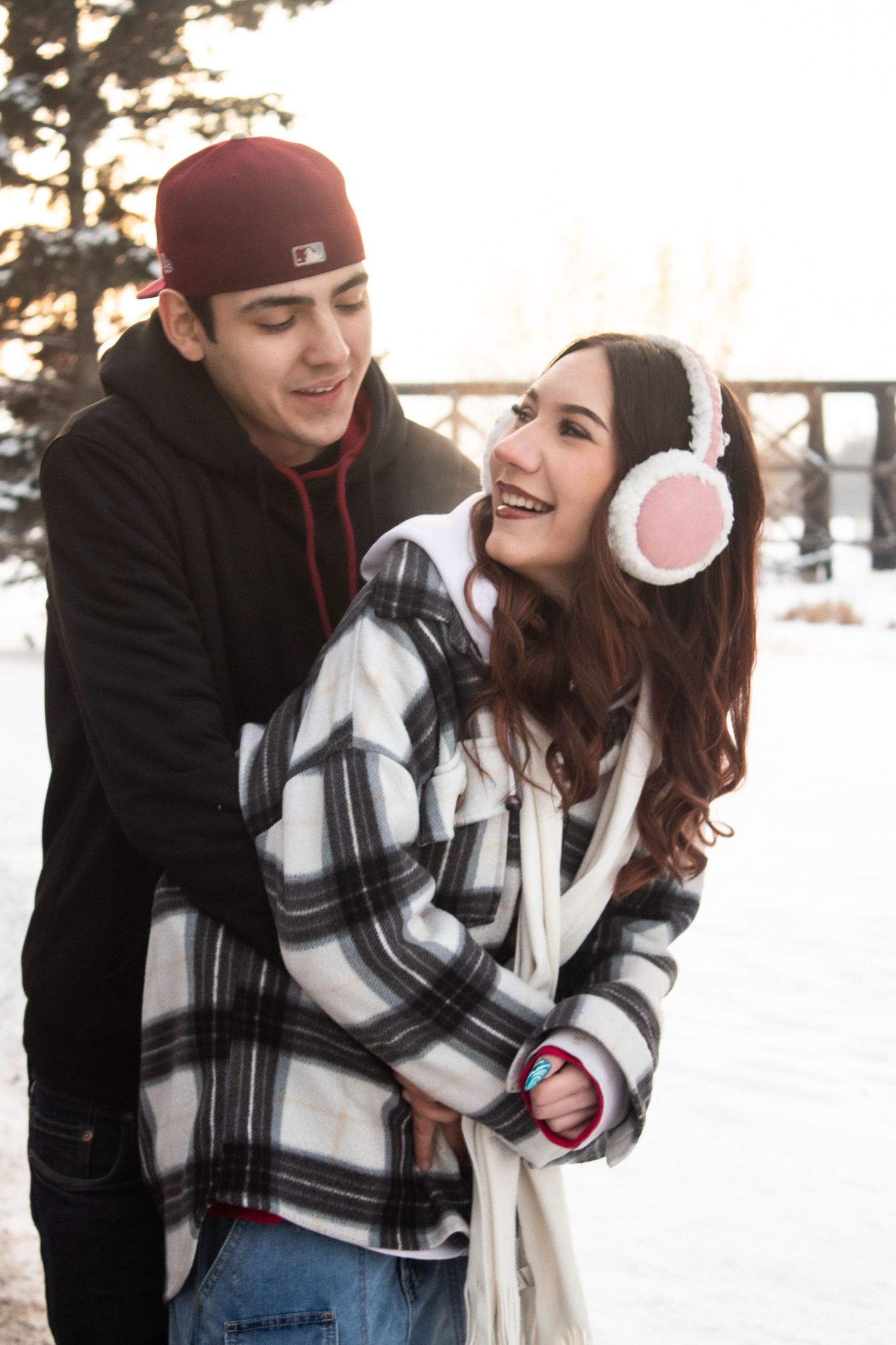 Winter couple portrait with person wearing fluffy earmuffs and plaid jacket.