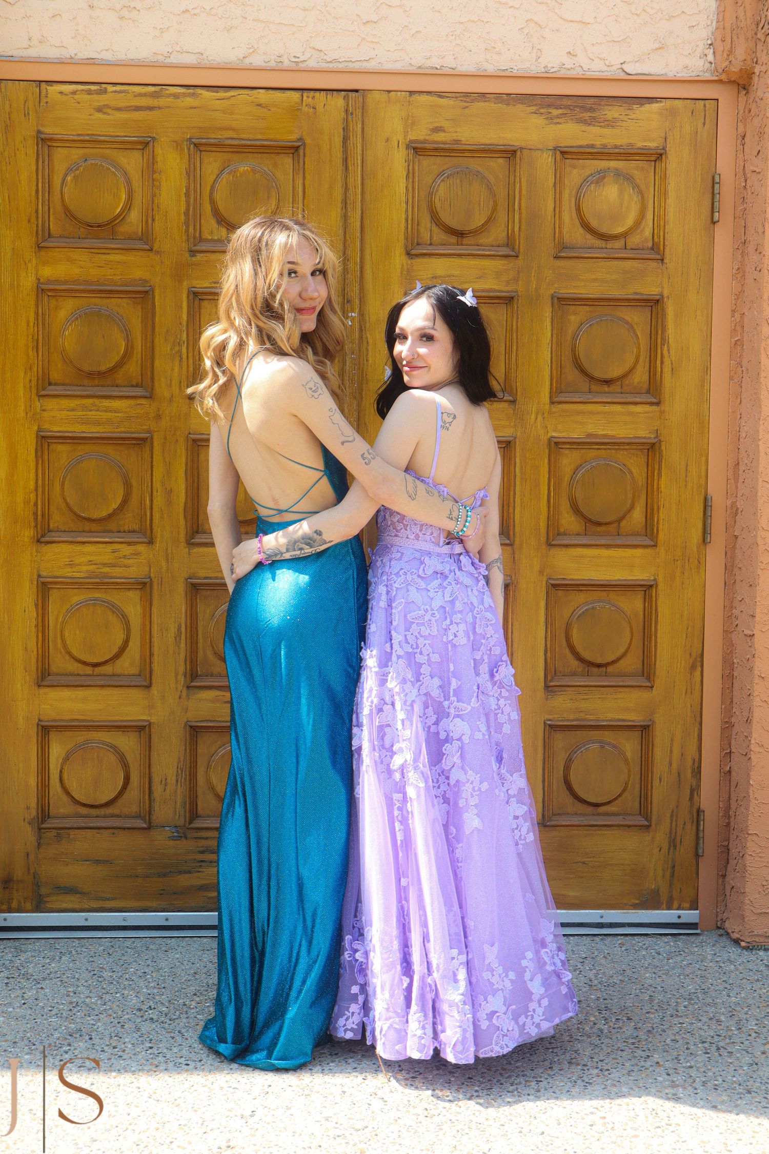 Two formal dresses - one turquoise and one lavender - photographed against decorative wooden doors.
