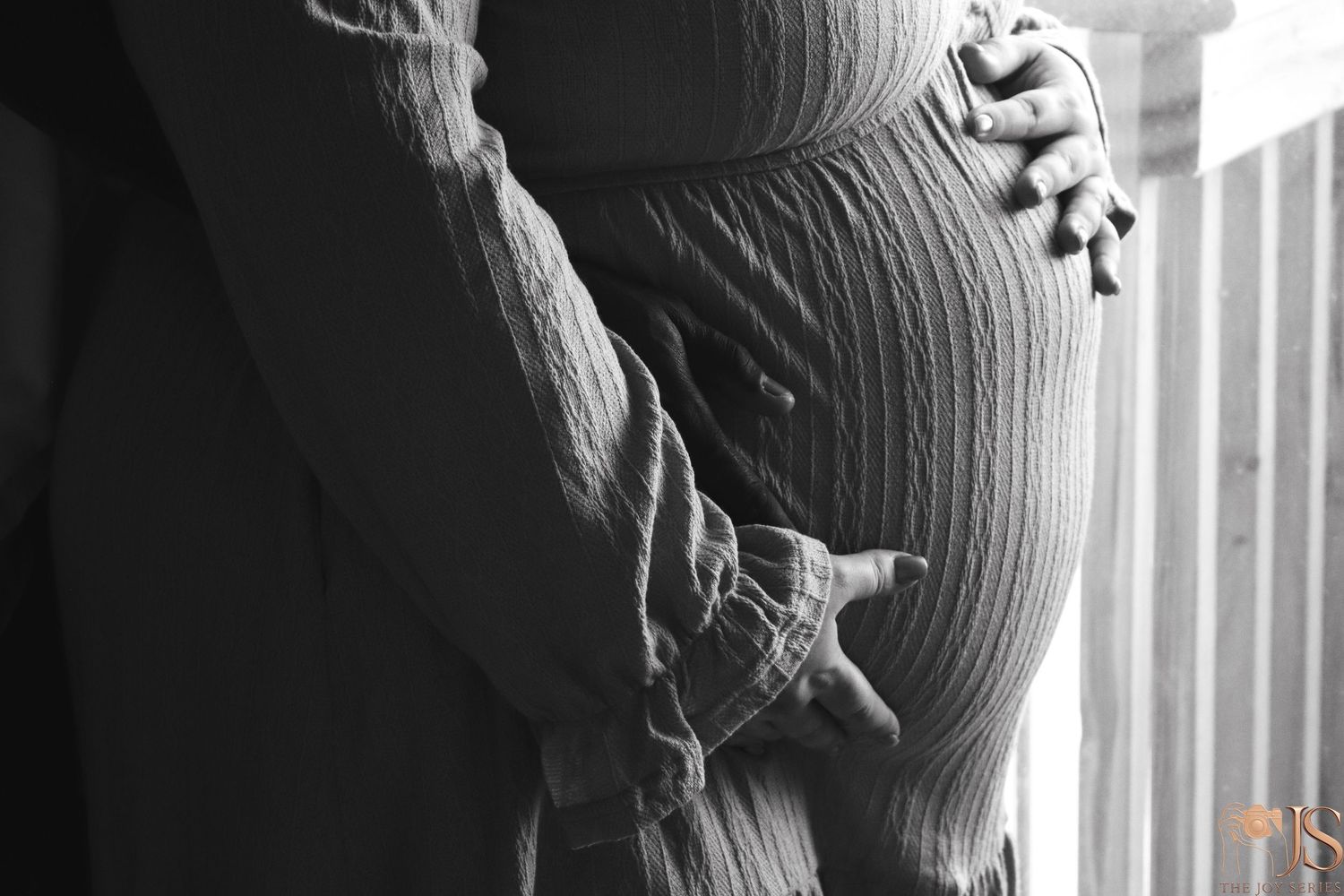 Black and white profile silhouette of a pregnant woman's belly against a window.