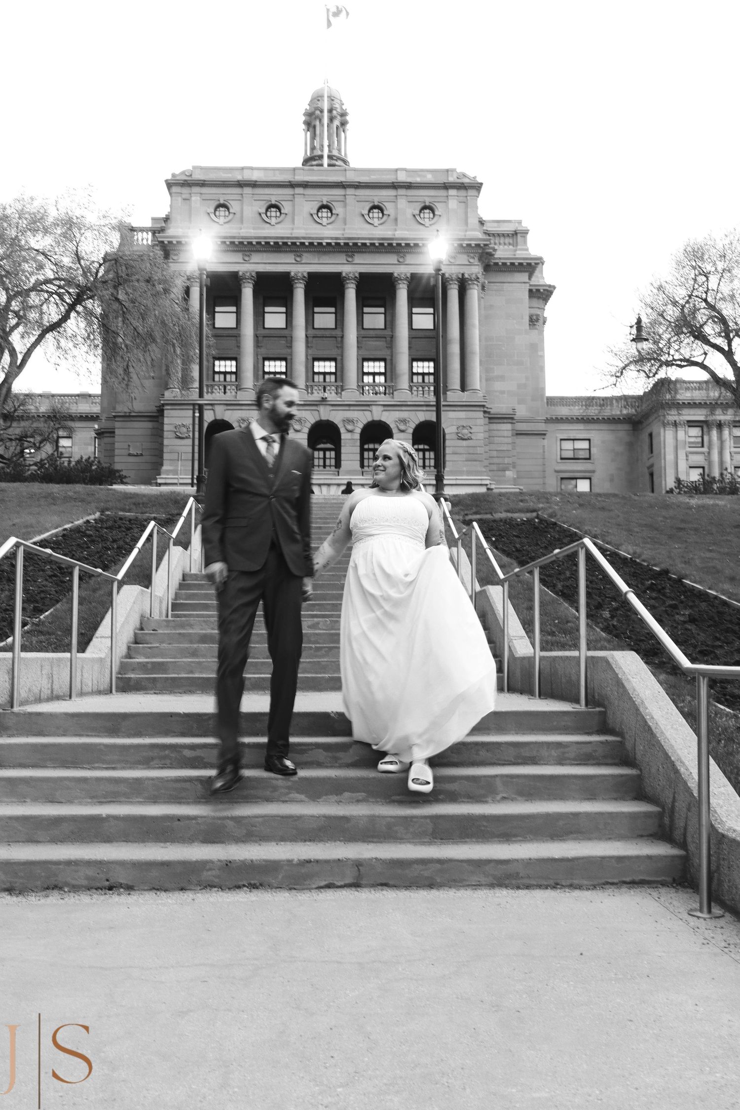 Black and white wedding photos show couple posing on grand stone steps in front of historic building facade.